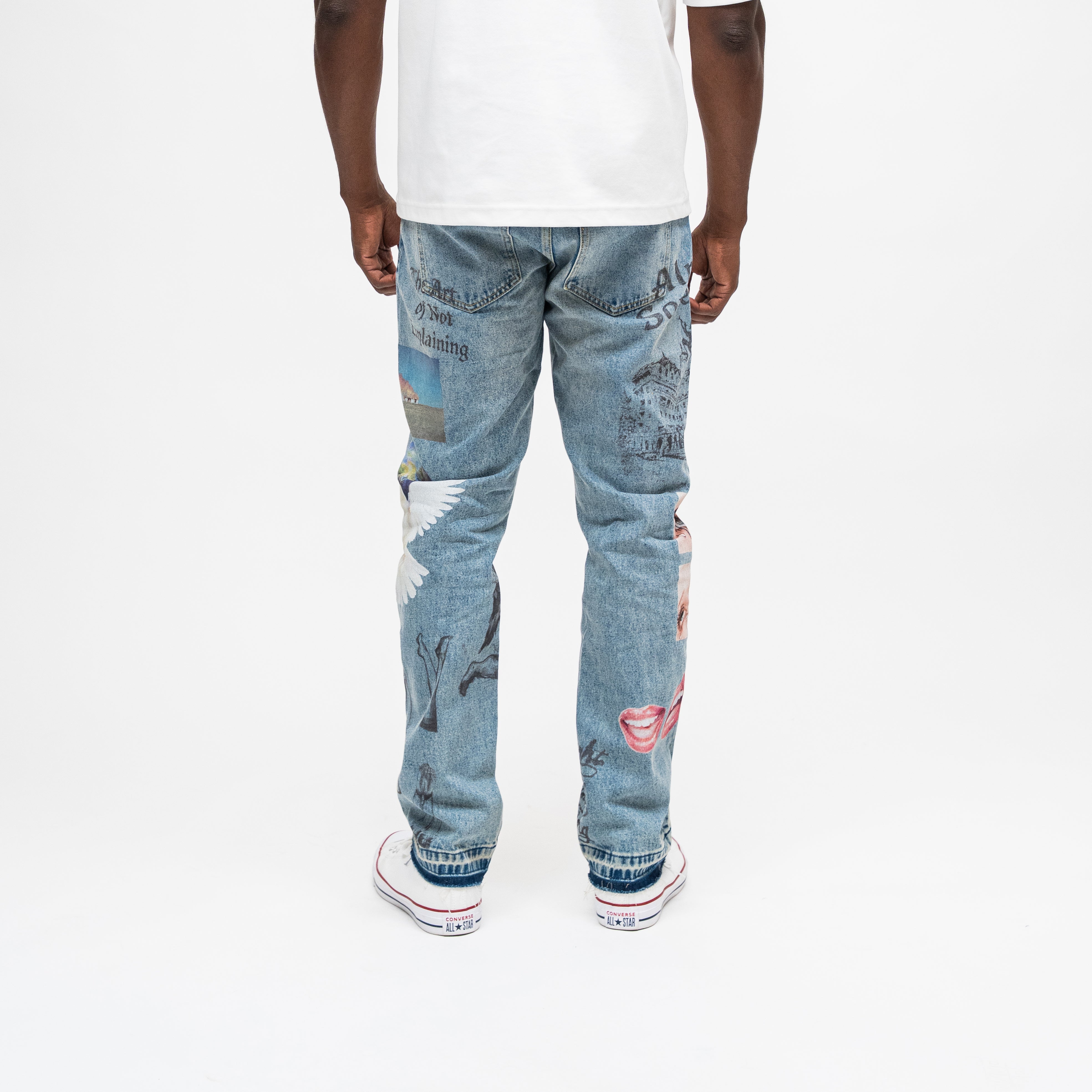 ALMOST SOMEDAY Gallery Denim Pant in Blue Wash, back view with Art of Not Explaining text, angel wings, lips, and architectural illustration