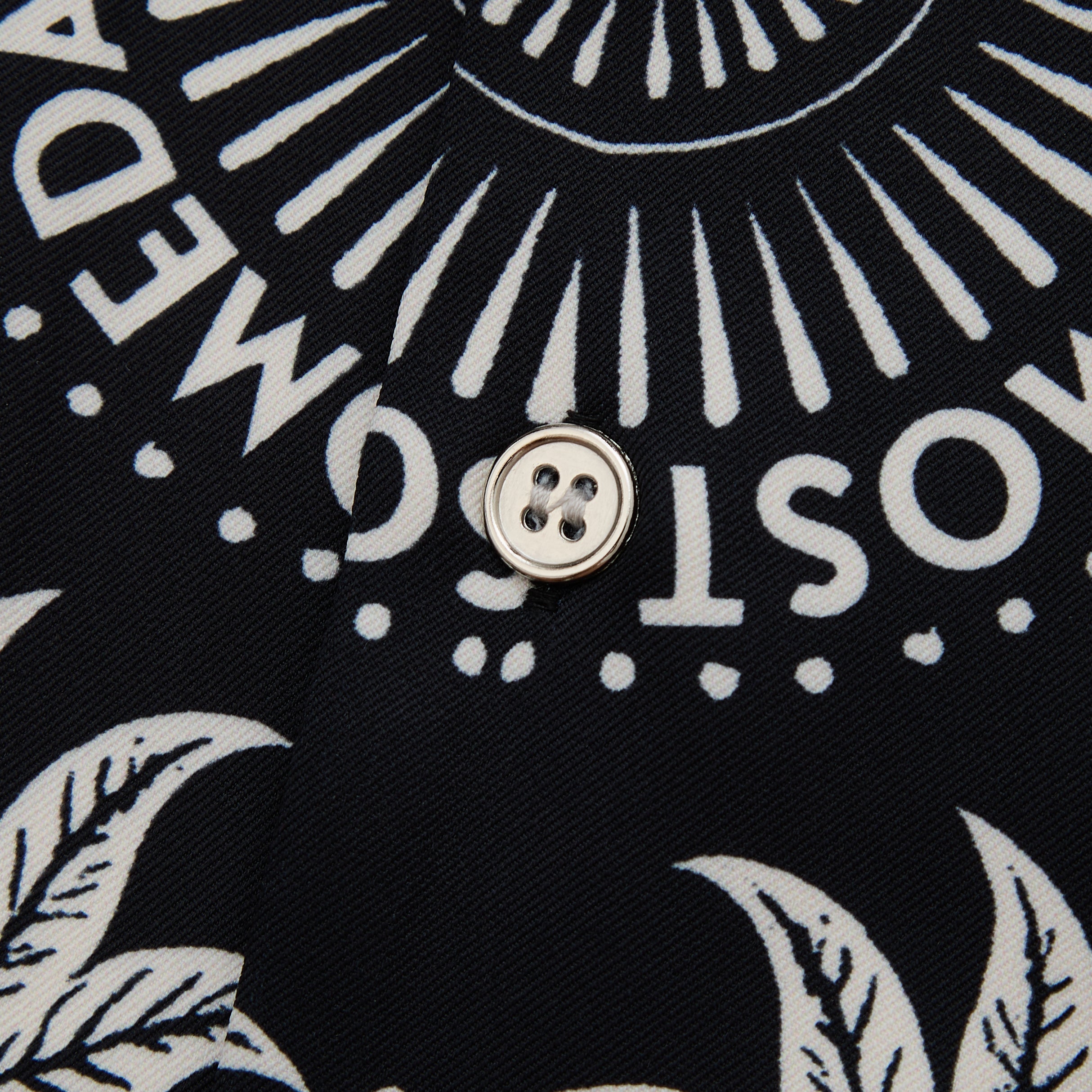 Close-up of a button on a black fabric with white text and patterns