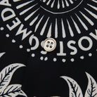 Close-up of a button on a black fabric with white text and patterns