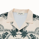Beige shirt with green floral and text pattern, brand label visible