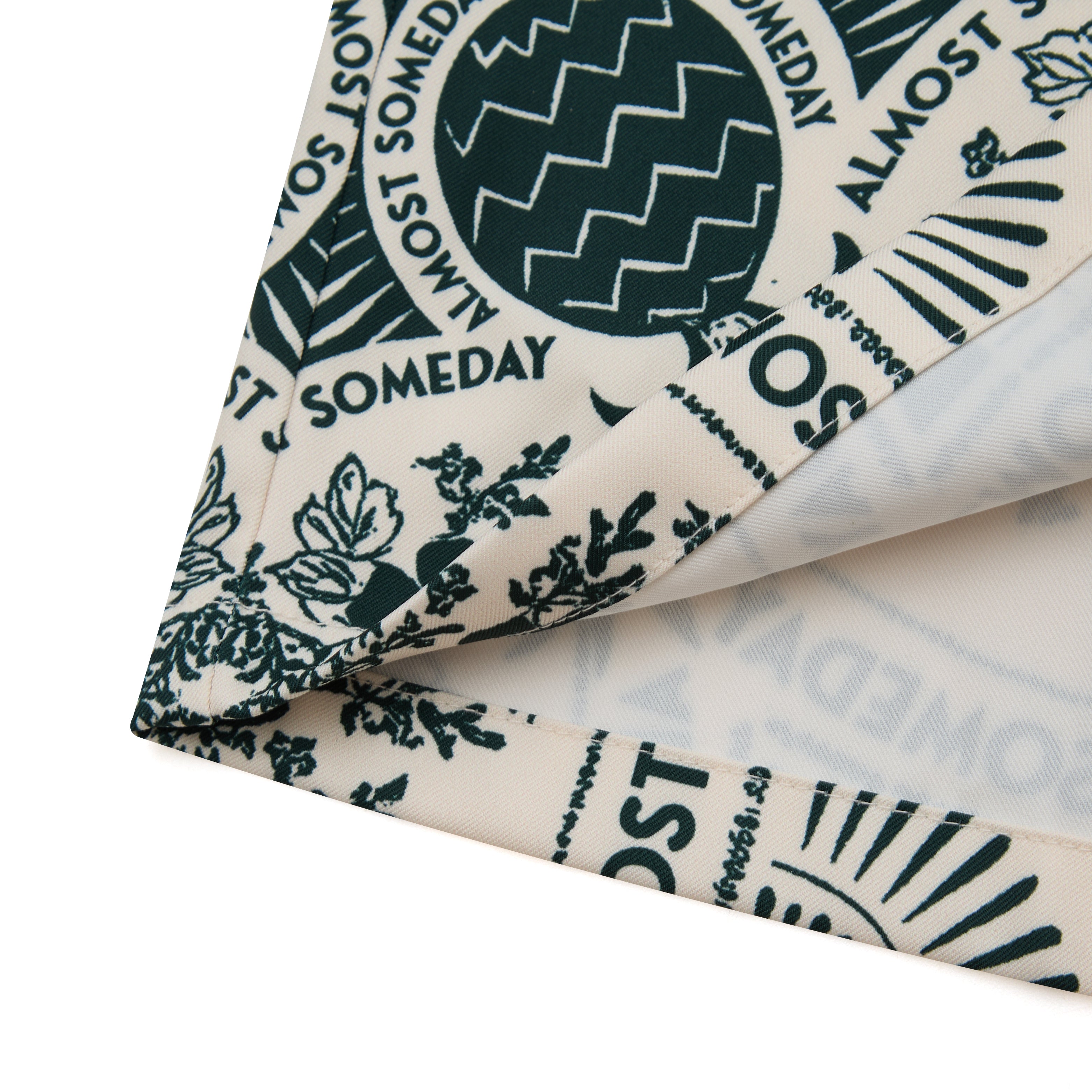 Folded fabric with 'ALMOST SOMEDAY' text and patterns on a white background