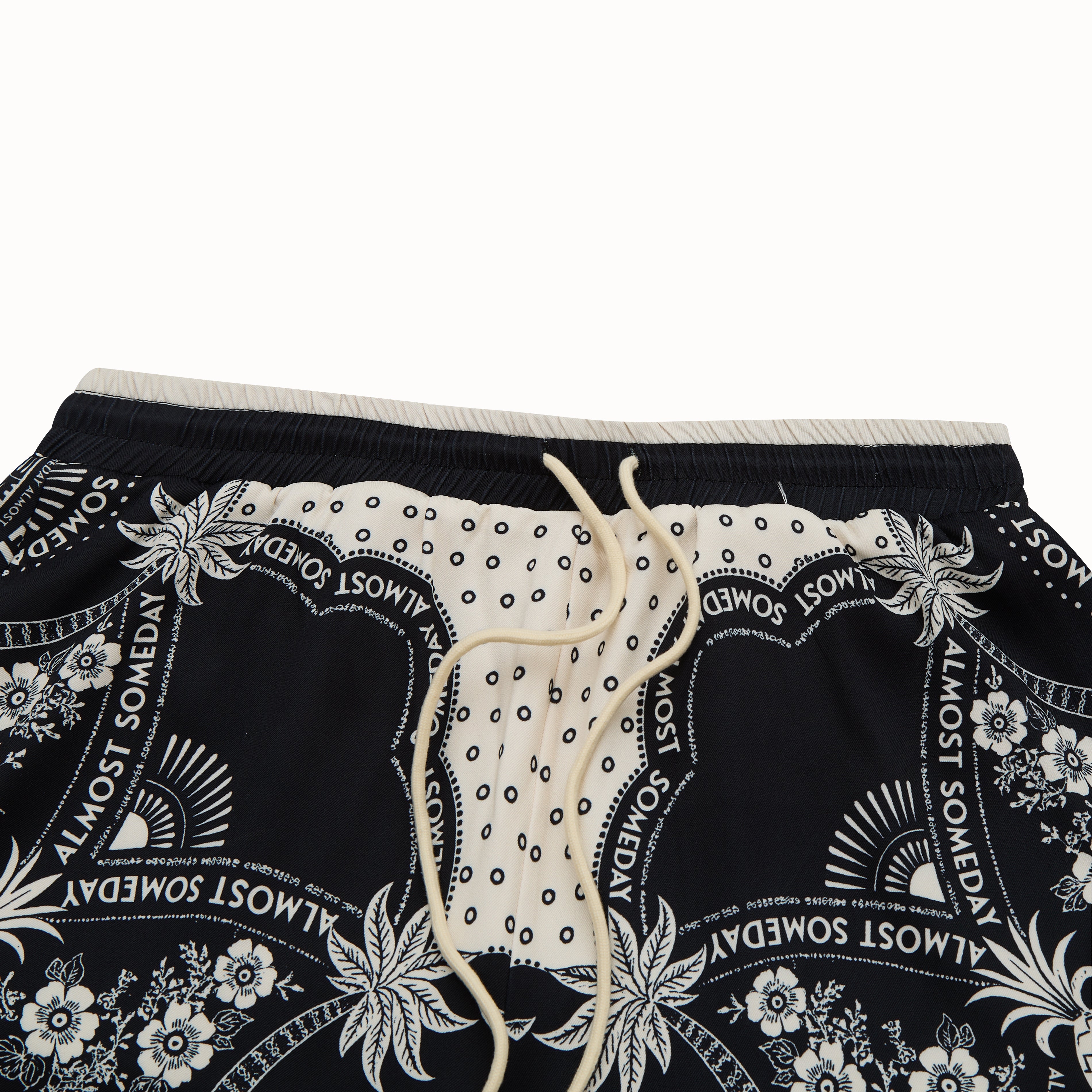 Black shorts with white floral and text pattern on a white background