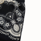 Black shorts with white floral and pineapple pattern on a white background