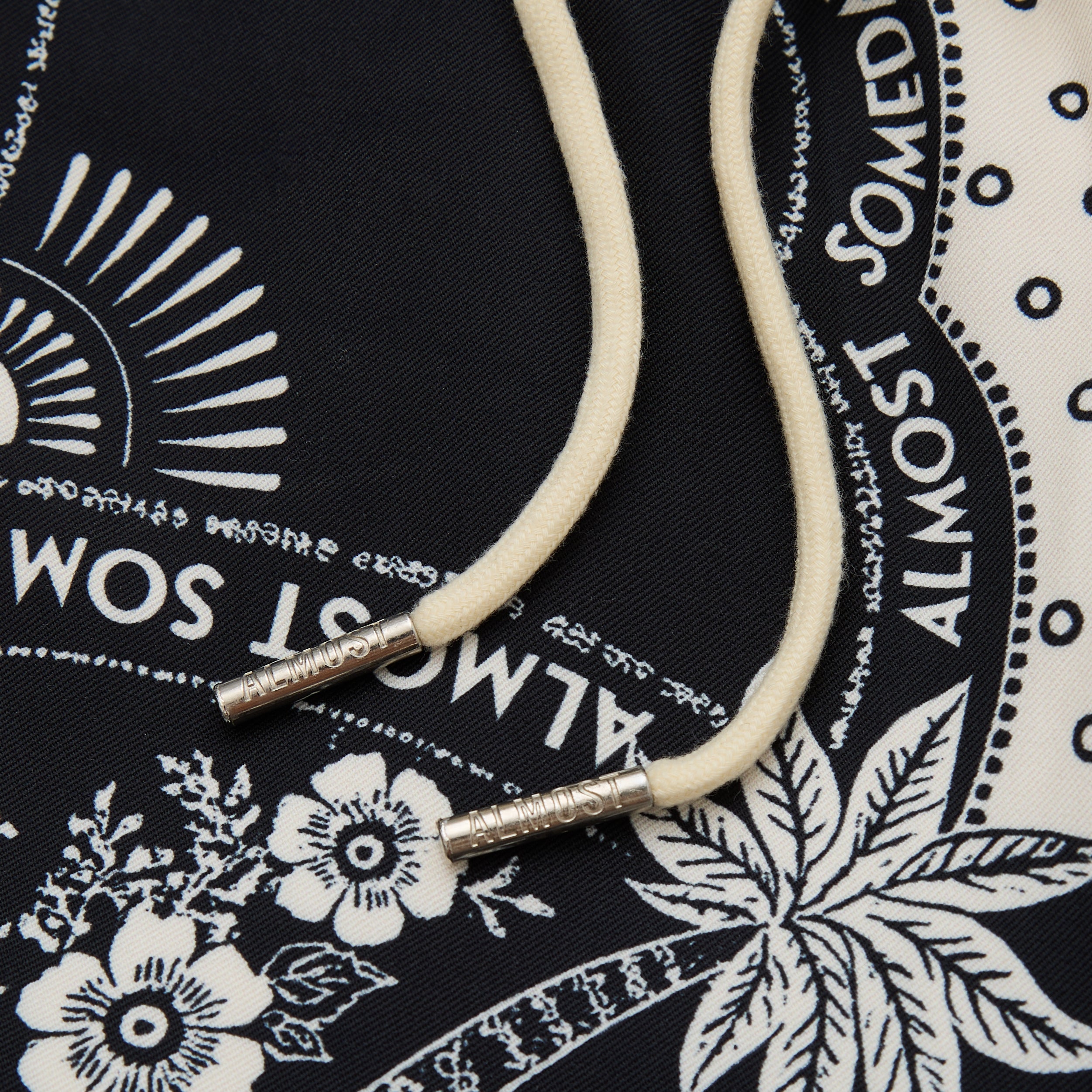 White cord with silver ends on a black bandana with white patterns