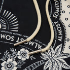 White cord with silver ends on a black bandana with white patterns
