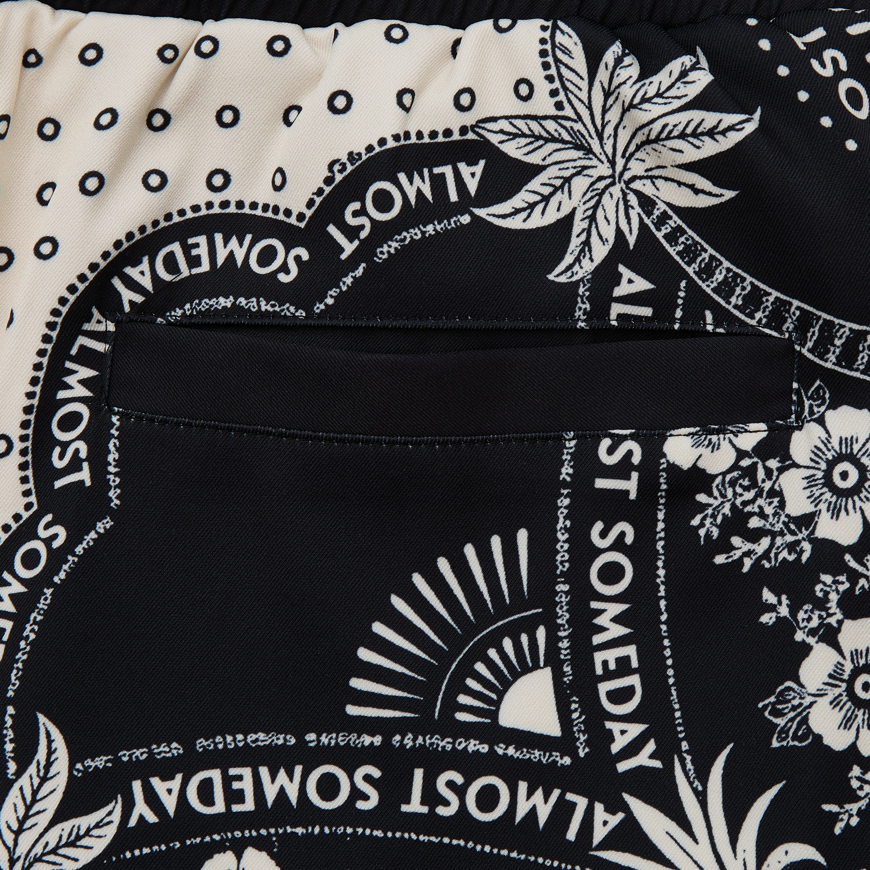 Close-up of a black and white patterned fabric with text and floral designs.