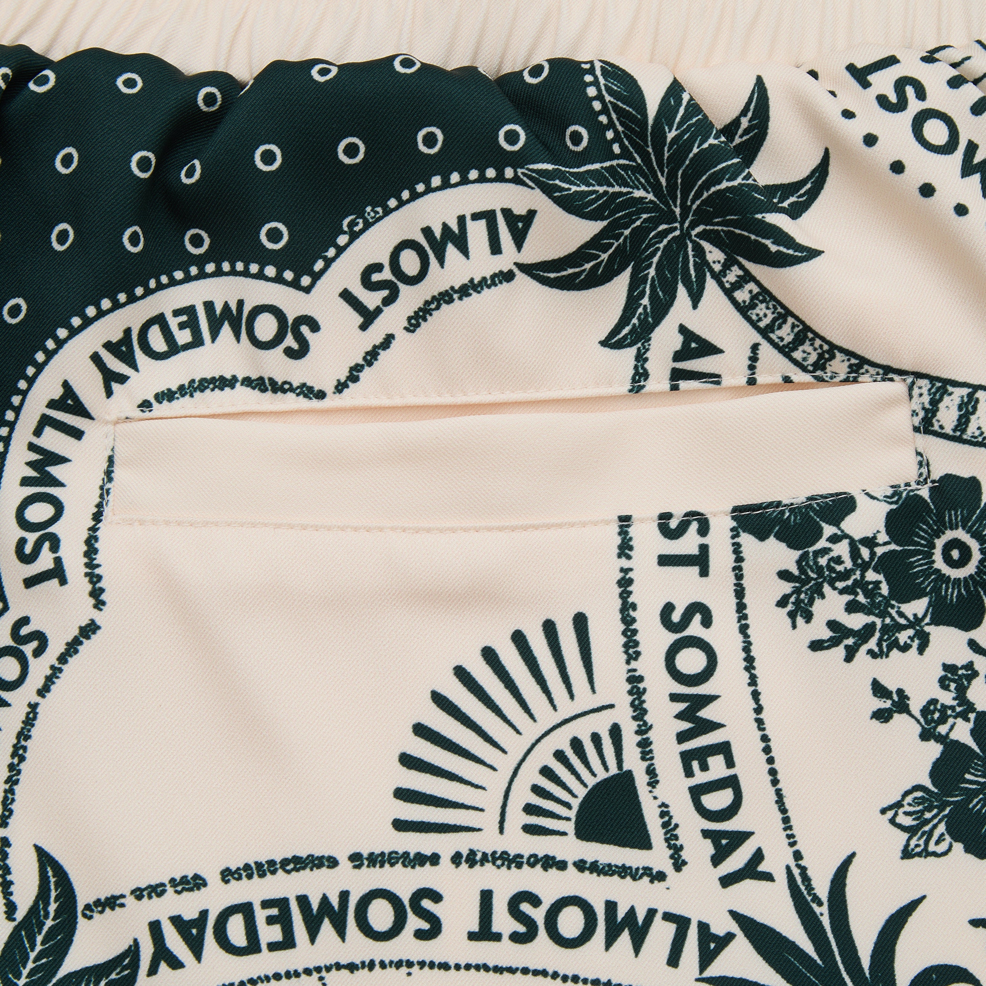 Close-up of a fabric with 'Almost Someday' text and floral patterns.