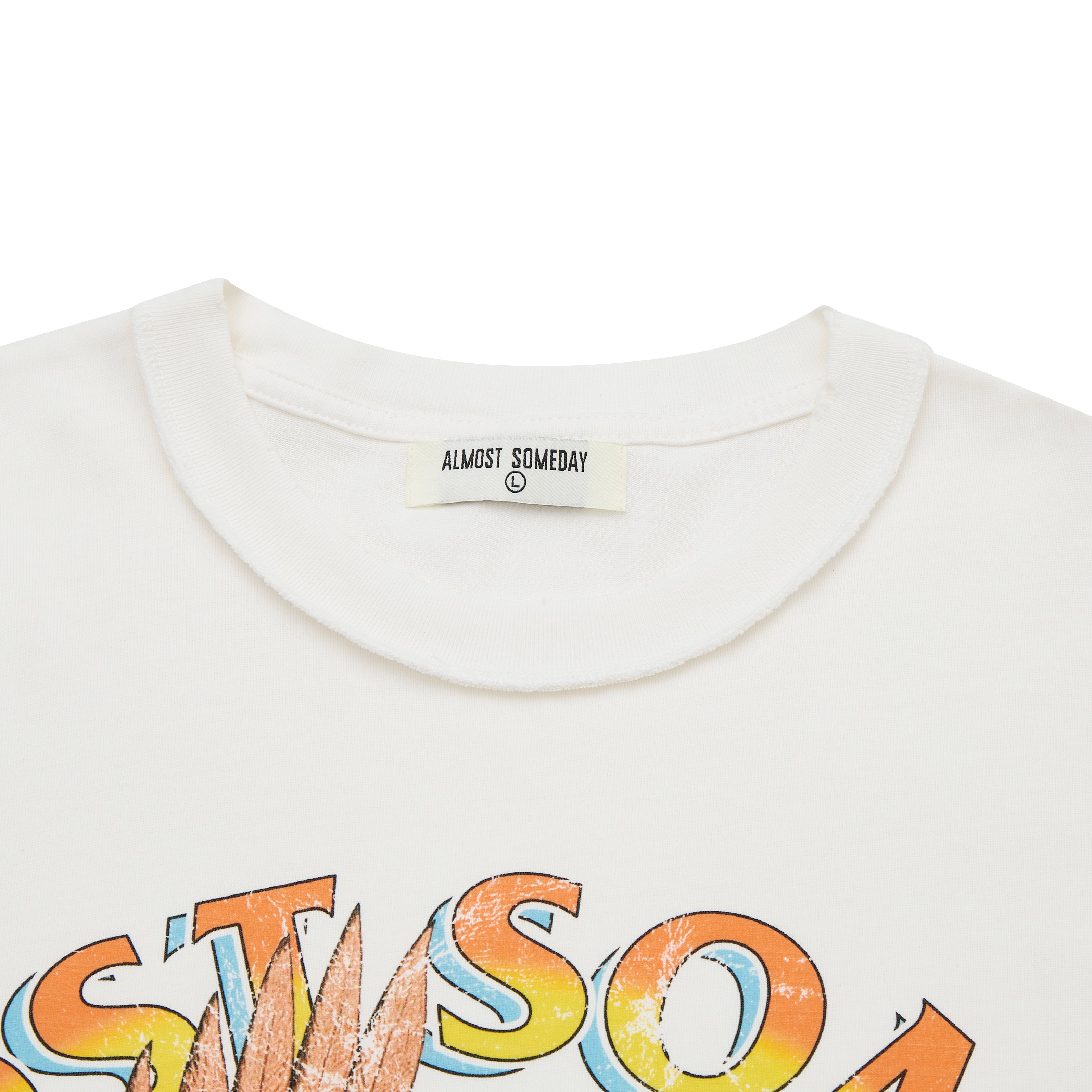 Cream t-shirt with colorful 'Almost Someday' graphic and brand label on a white background