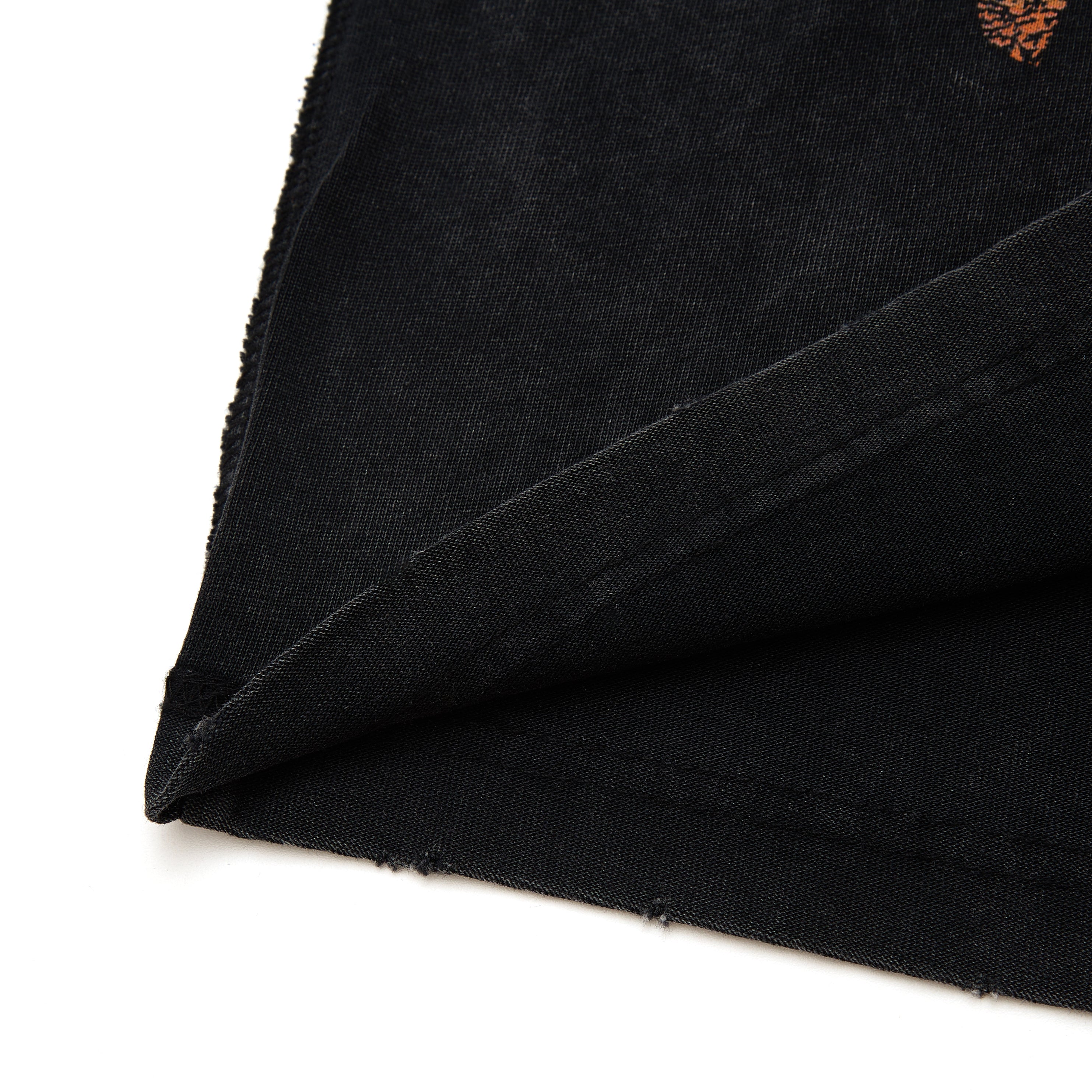 Close-up of black fabric with a small orange logo on a white background