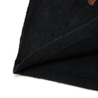 Close-up of black fabric with a small orange logo on a white background