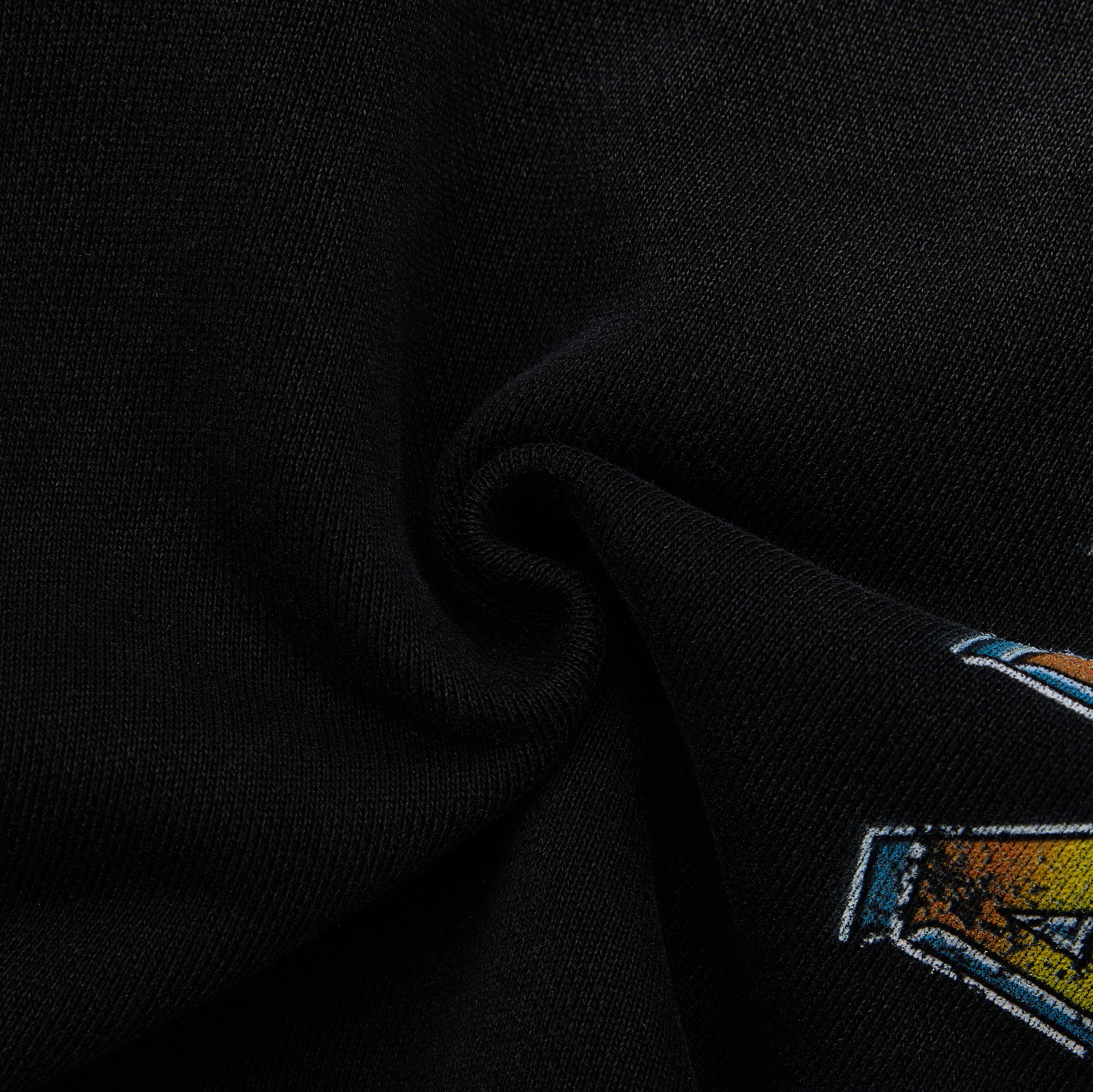 Close-up of a black fabric with a colorful logo on a dark background