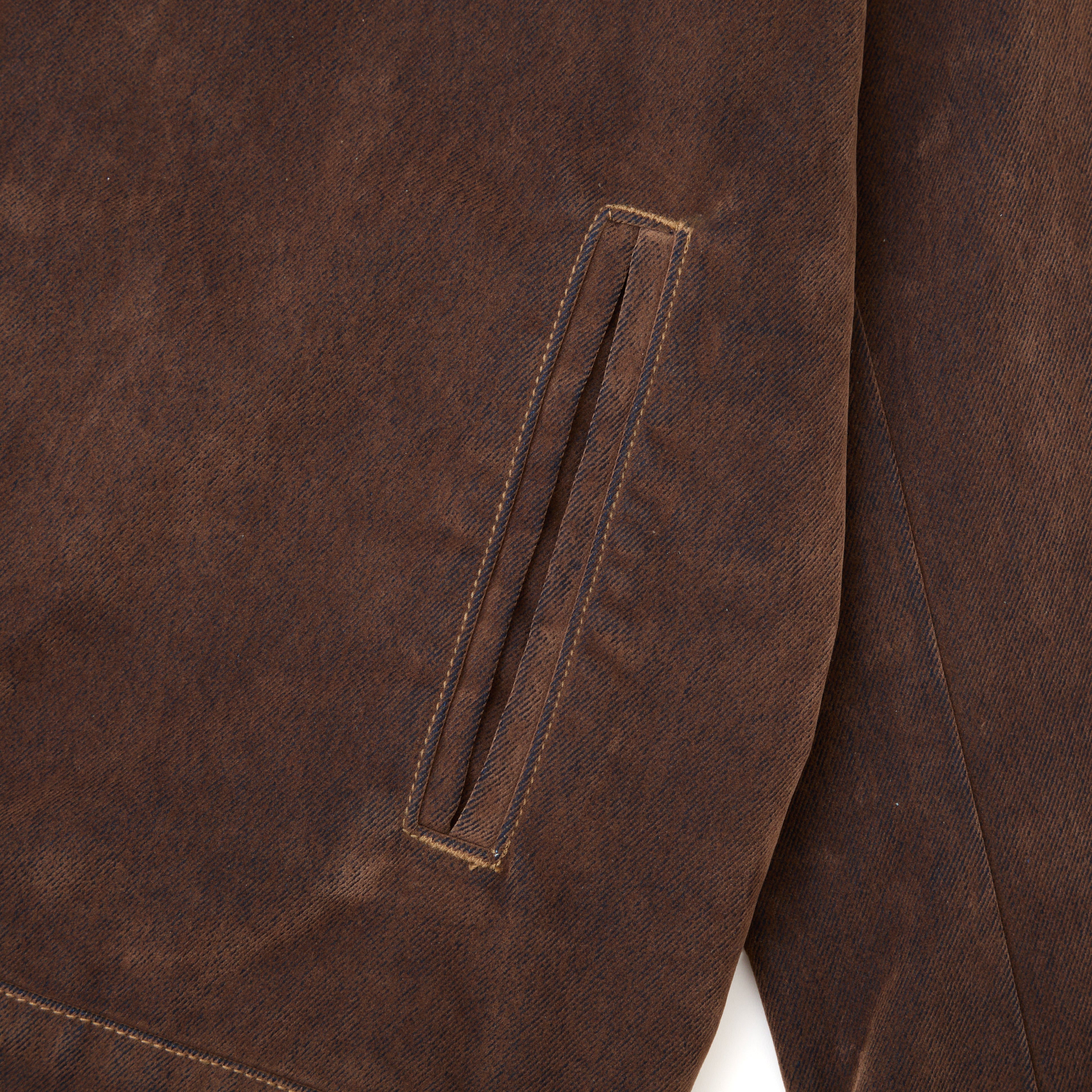 Close-up of a brown fabric with a pocket detail on a white background