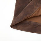 Close-up of brown leather fabric with visible stitching on a white background