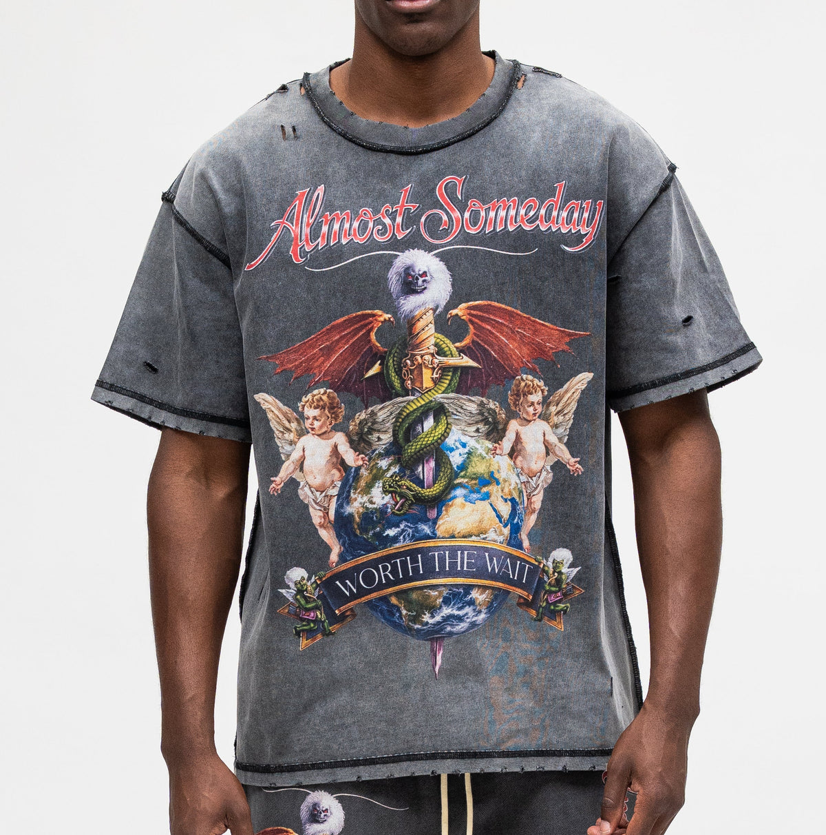 A man modeling a distressed gray graphic t-shirt with a 'Almost Someday' design, paired with matching gray sweatpants, against a plain light gray background.