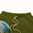 Olive green sweatpants with a scenic print on the leg and white drawstring.