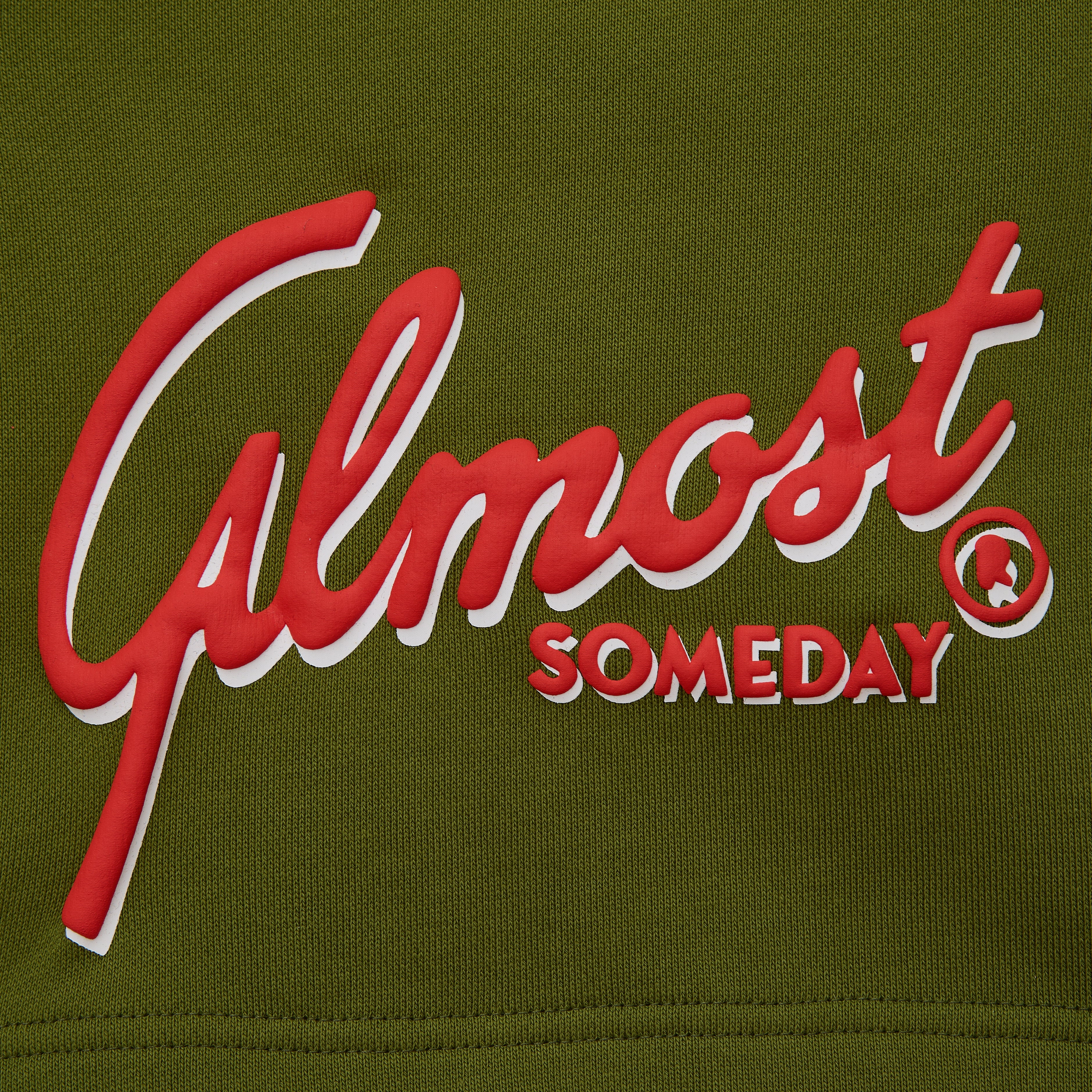 Red and white 'Almost Someday' logo on olive green fabric
