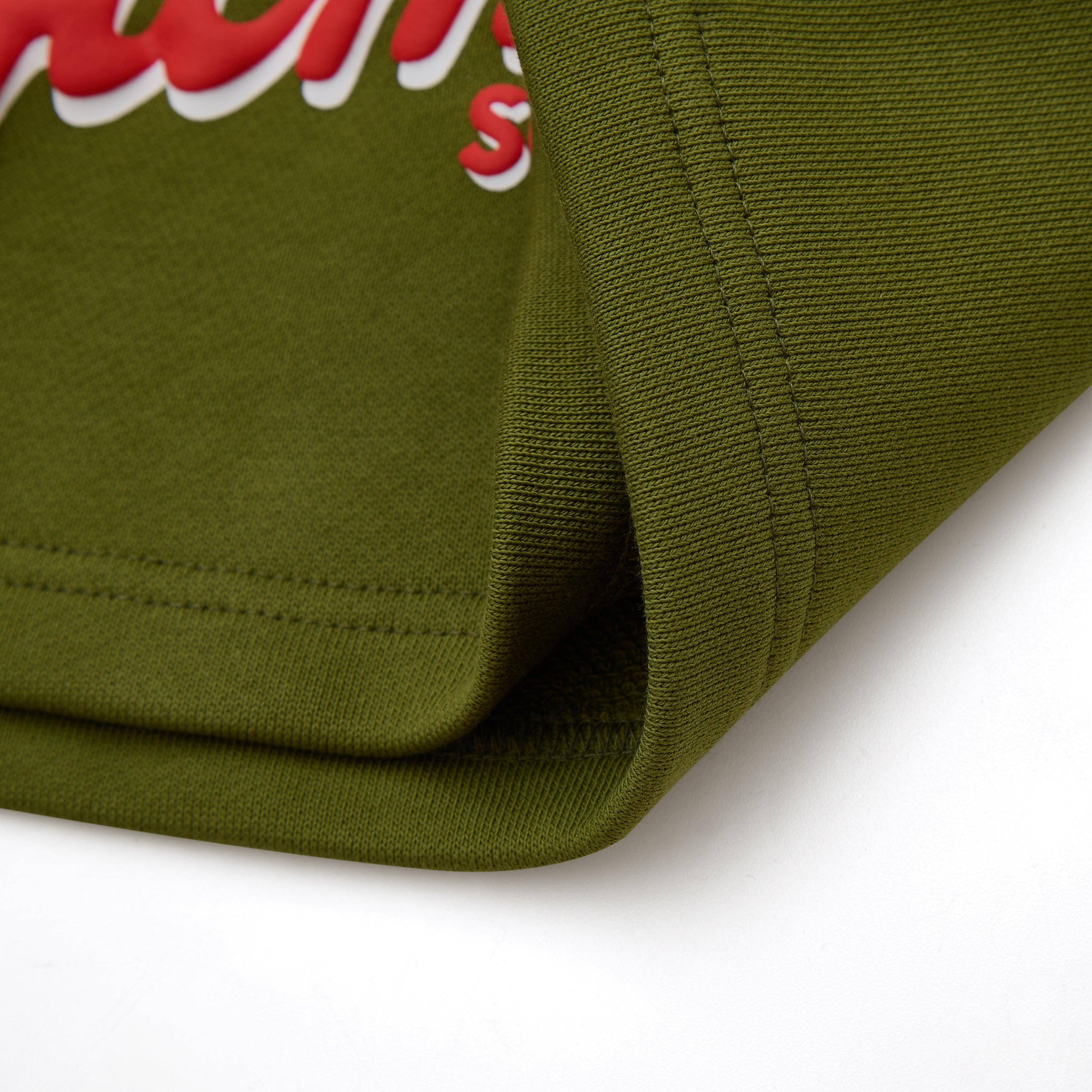 Close-up of an olive green fabric with red and white text on a white background