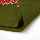 Close-up of an olive green fabric with red and white text on a white background