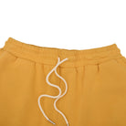 Mustard yellow sweatshorts with a white drawstring on a white background