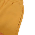 Close-up of mustard yellow sweatshorts on a white background