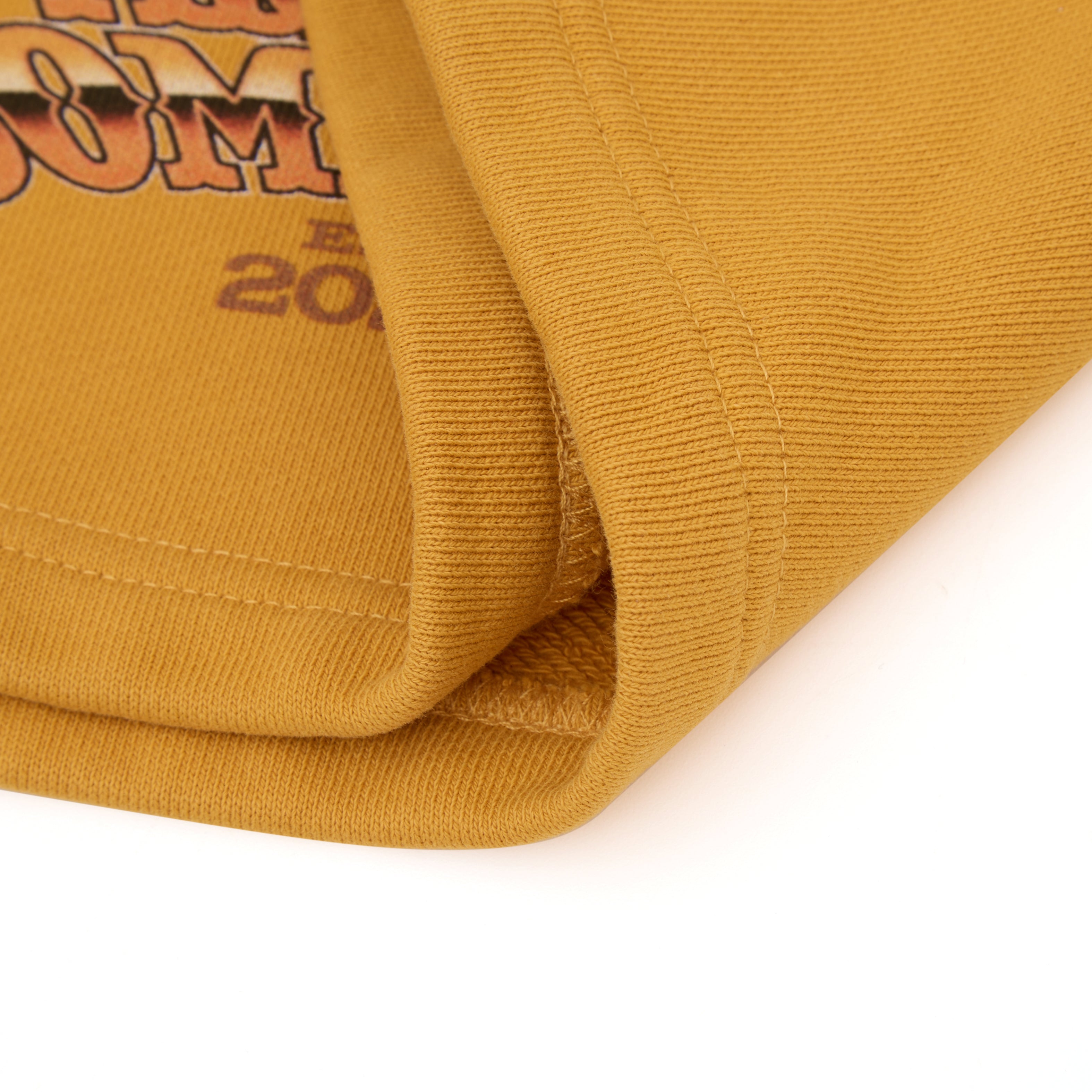 Close-up of a mustard yellow sweatshorts fabric with text on a white background