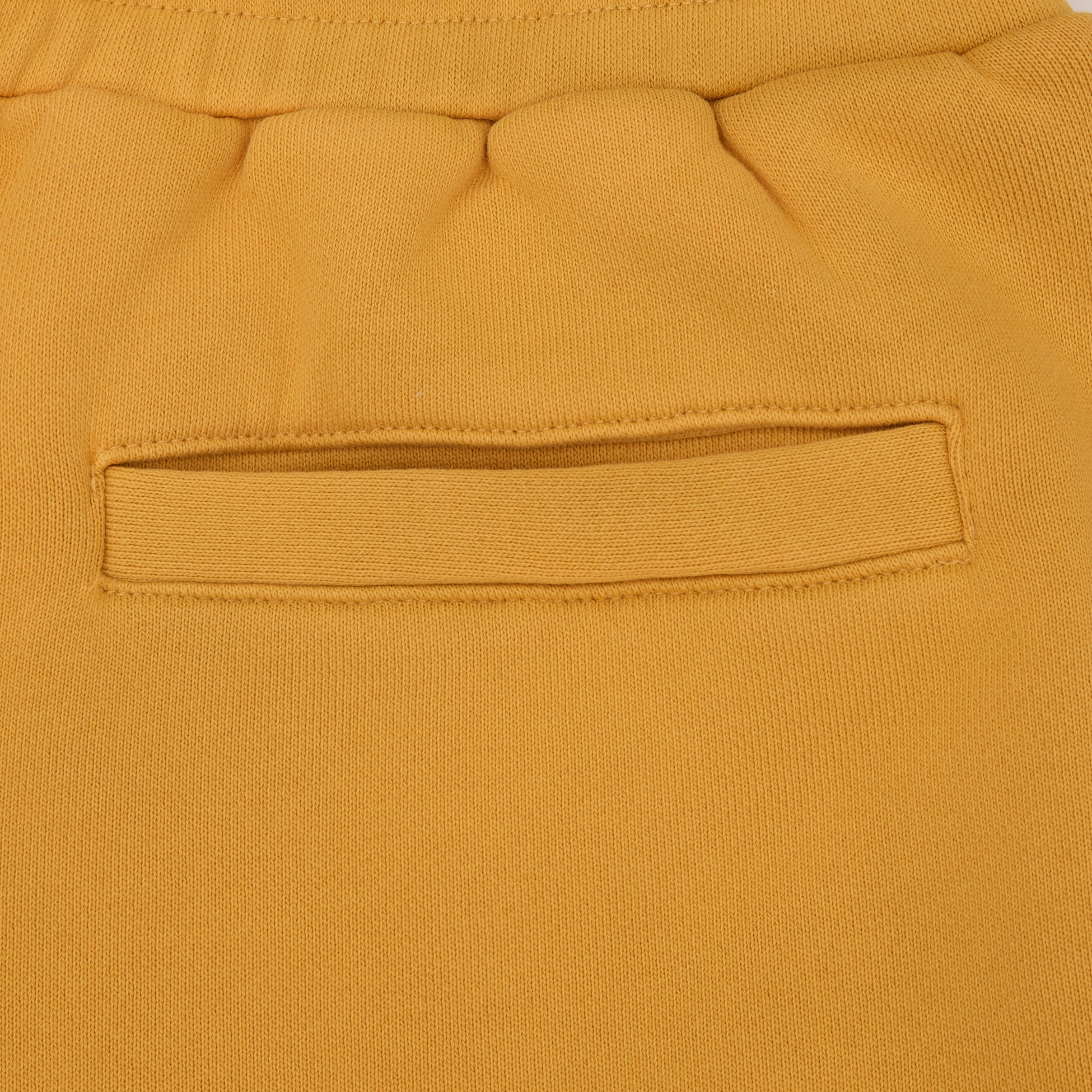 Close-up of mustard yellow sweatshort fabric with a pocket detail