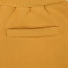 Close-up of mustard yellow sweatshort fabric with a pocket detail