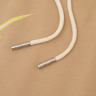 White drawstring with metal eyelets on a beige fabric background