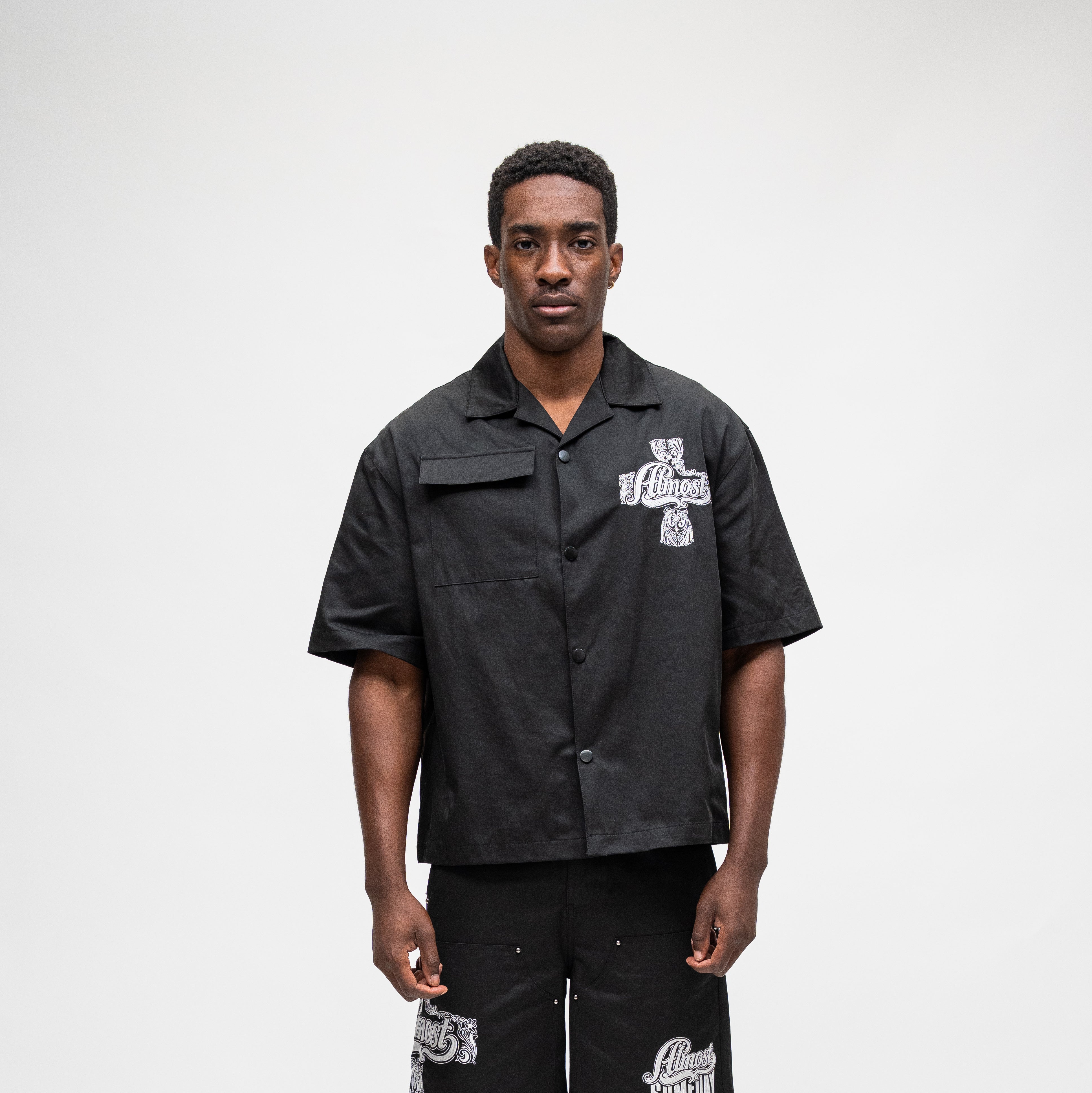 ALMOST SOMEDAY Vision Nylon Shirt in Black, front view with ornate cross graphic on right chest and utility pocket