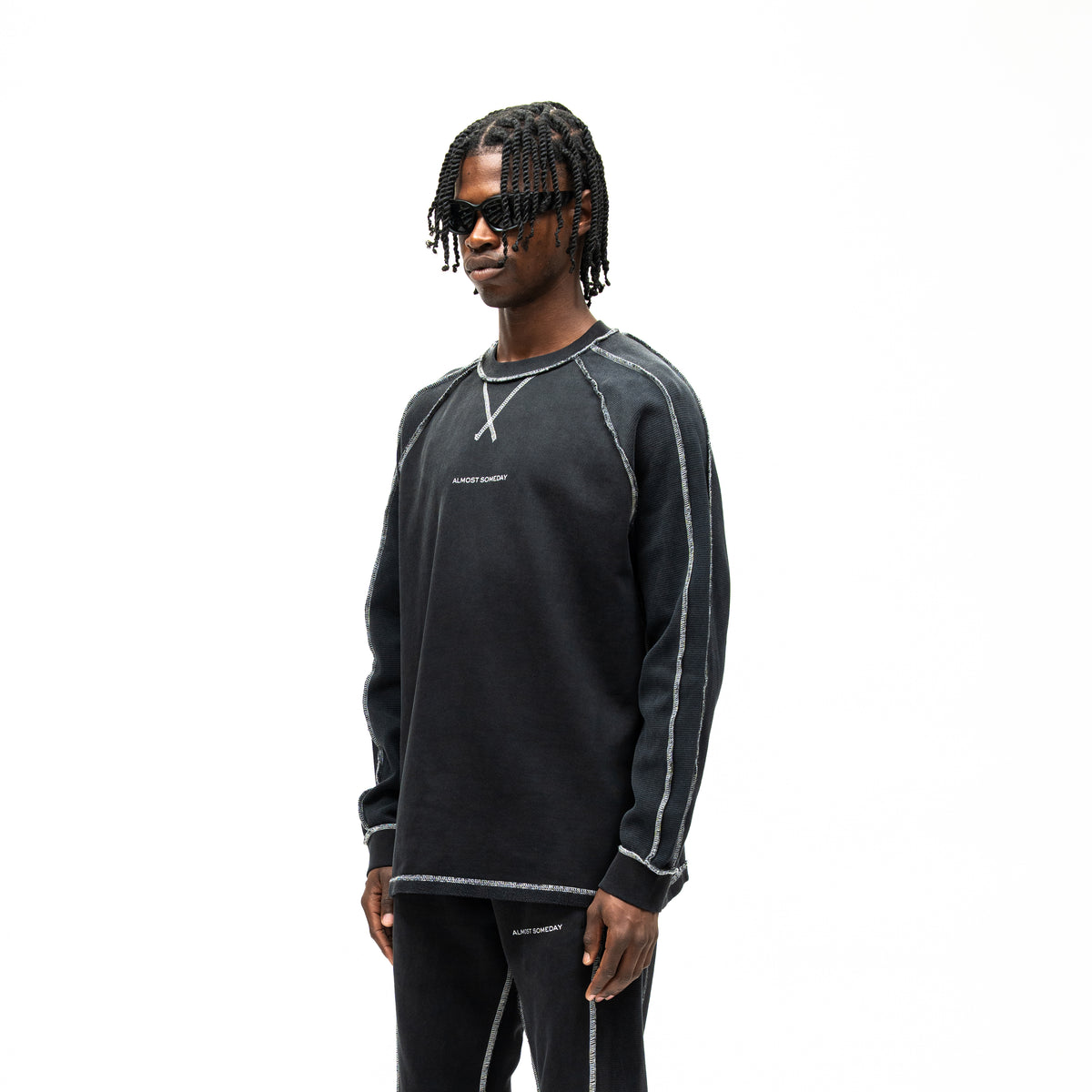 Alumni Crewneck – Black – Three-quarter front view on model showing chest logo and contrast-stitched sleeve panels