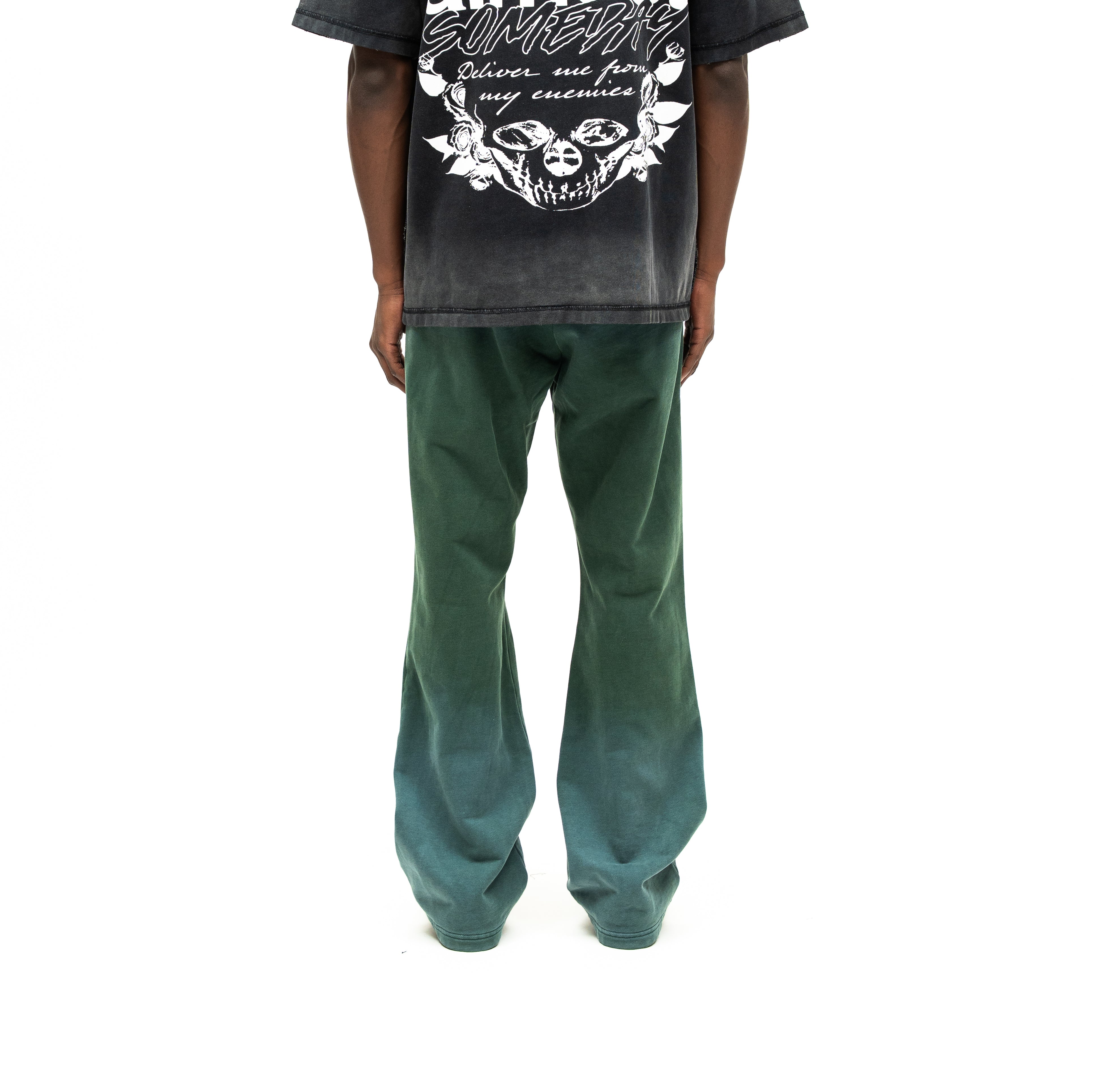 Enemies Flare Bottoms – Green – Back view on model styled with a black graphic tee, showing flared legs and faded green finish
