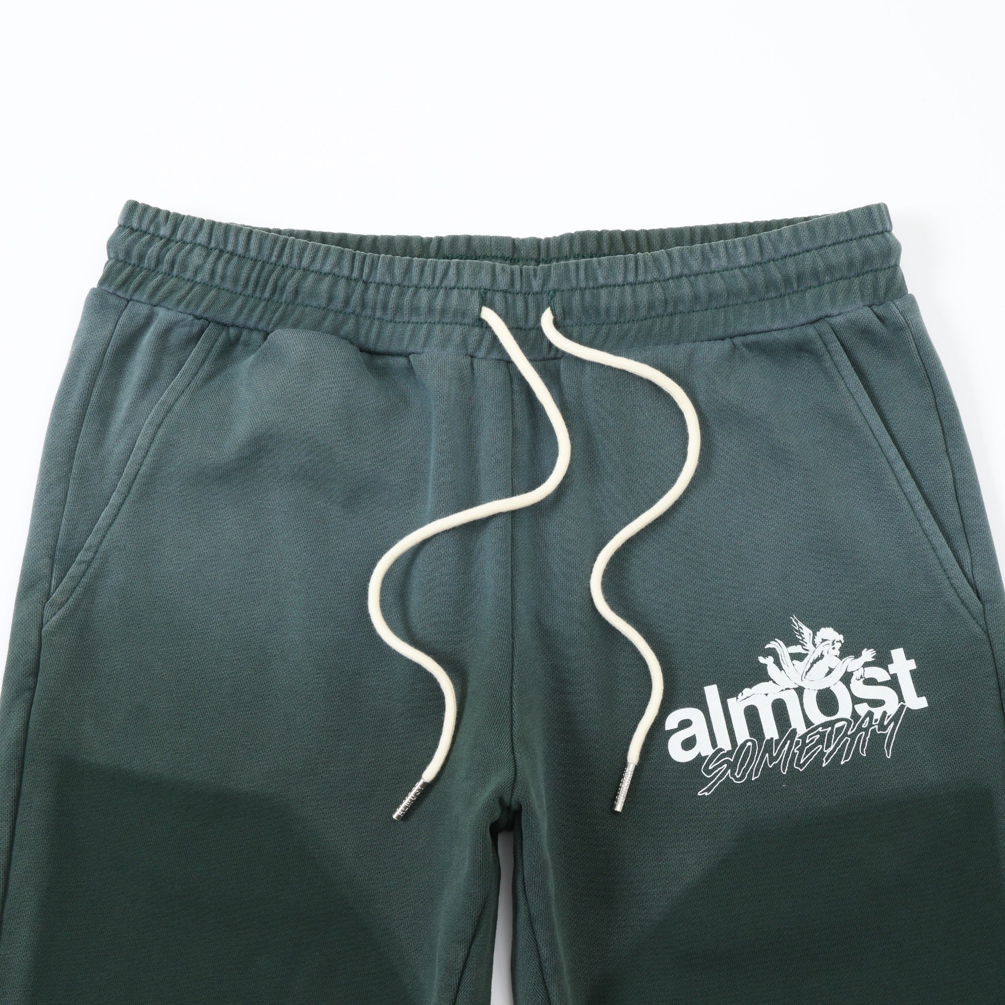 Enemies Flare Bottoms – Green – Close-up of elastic waistband, white drawstrings, angled pockets, and white thigh logo