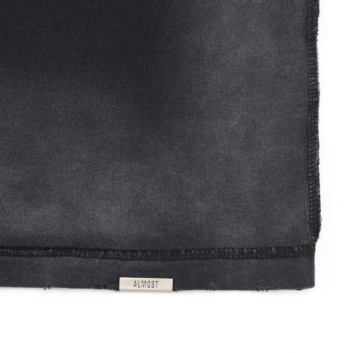 Enemies Tee – Black – Close-up of bottom hem with metal ALMOST logo tab