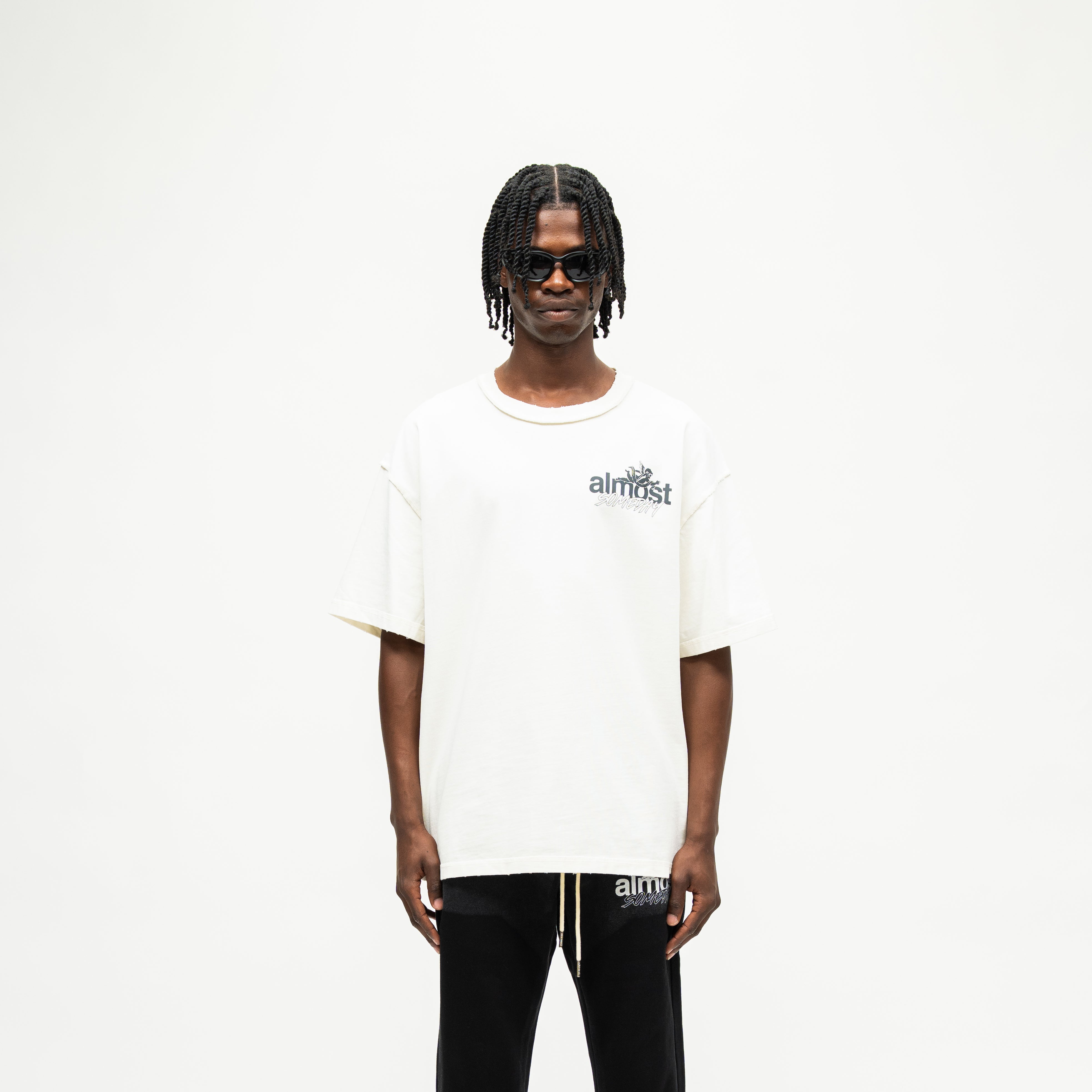 Enemies Tee – Cream – Front view on model showing black chest logo, short sleeves, and boxy fit