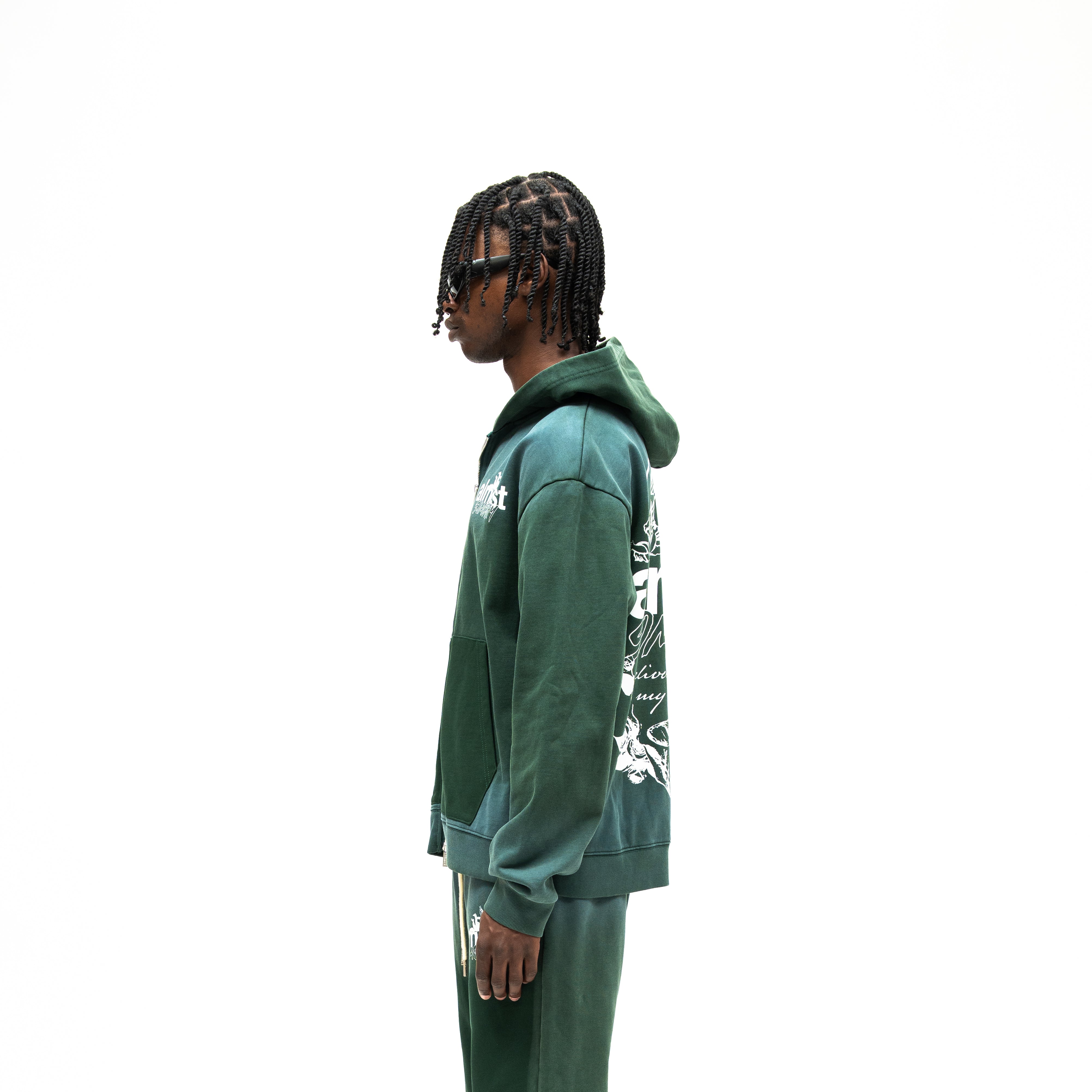 Enemies Zip Hoodie – Green – Side view on model showing hood, long sleeves, and partial white back graphic