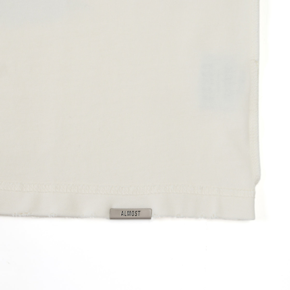 Fountain Tee – Cream – Bottom hem detail with ALMOST label