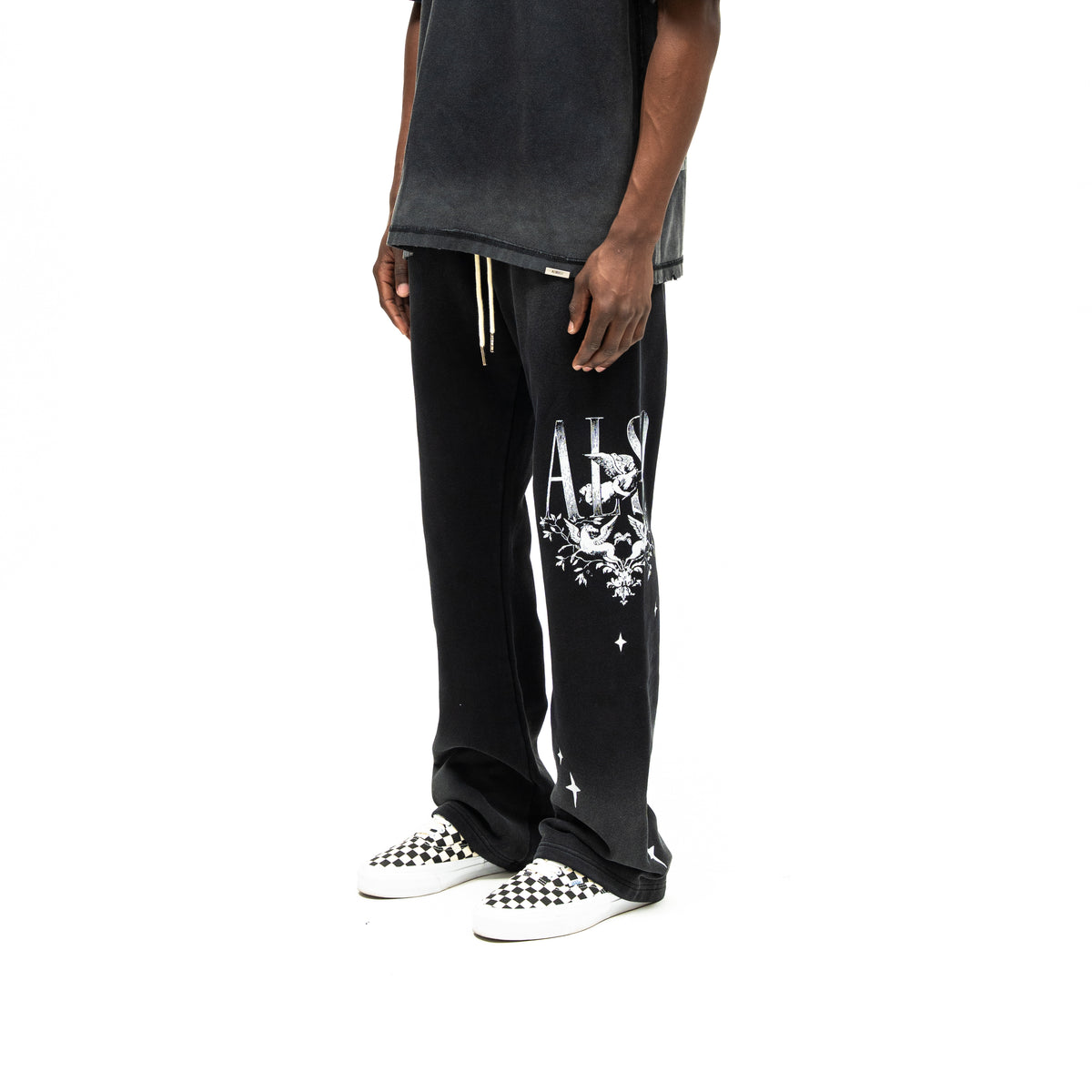League Flare Sweatpants – Black – Three-quarter front view on model styled with a tee, showing white cherub and star leg graphics