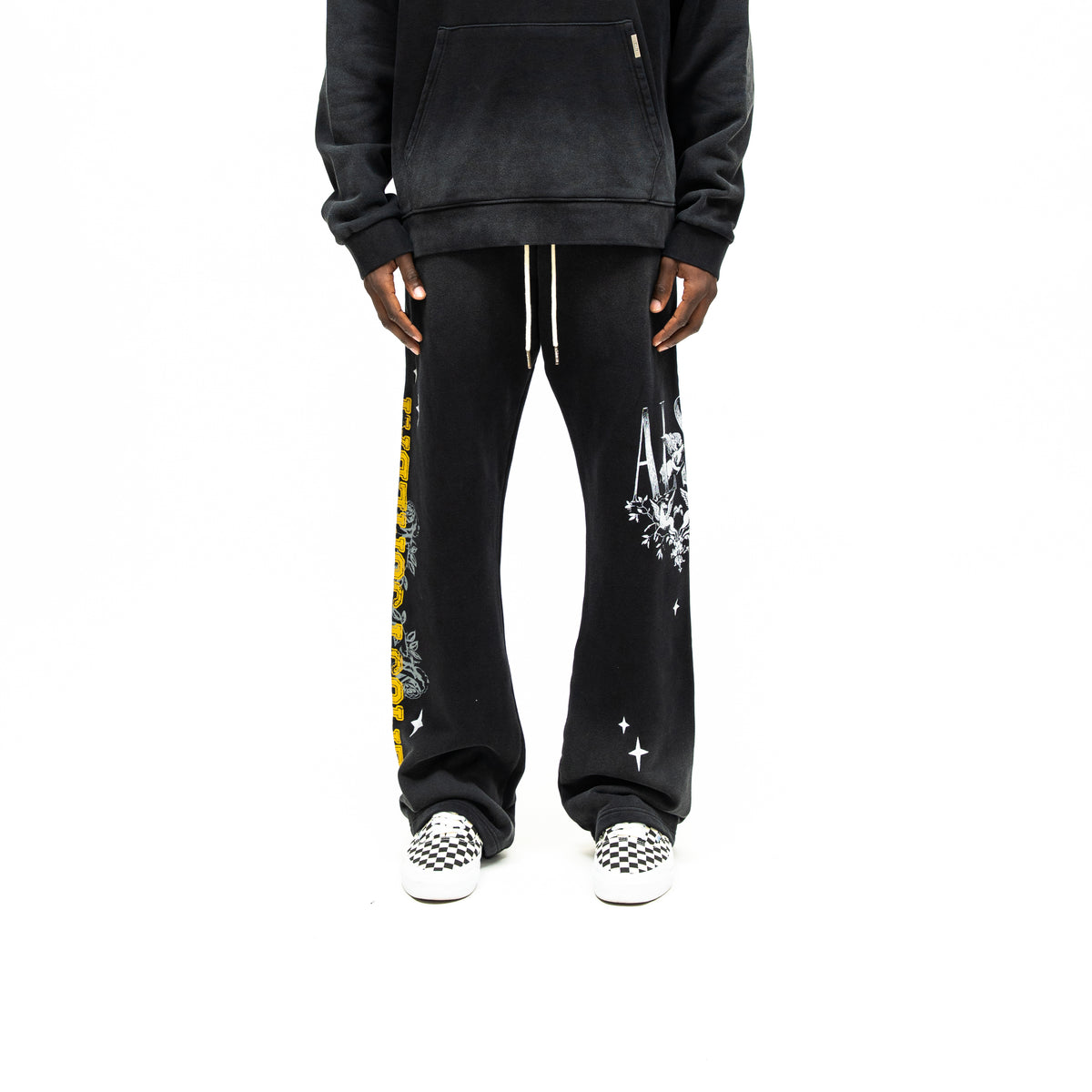 League Flare Sweatpants – Black – Front view on model styled with a hoodie, showing white drawstrings and contrasting leg graphics