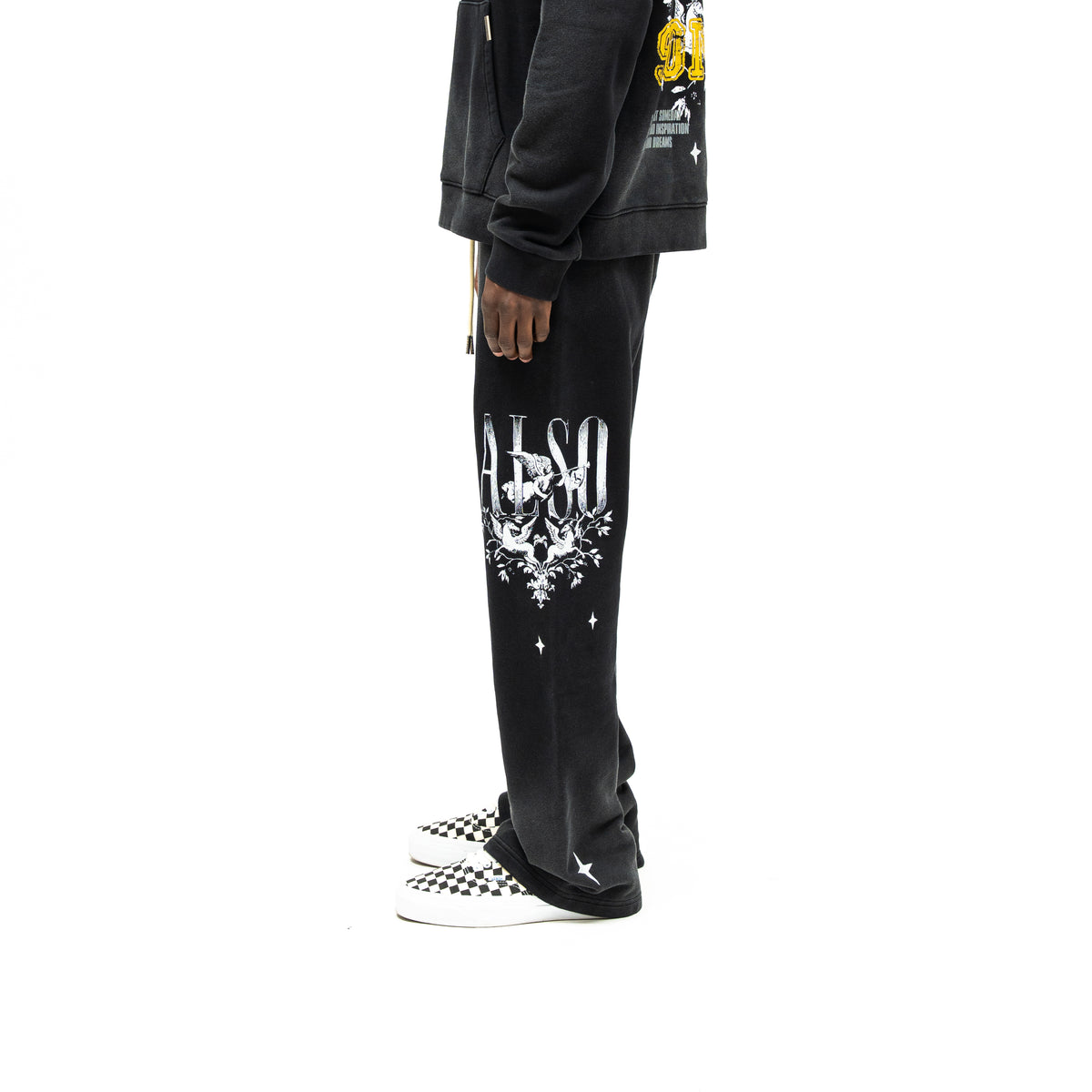 League Flare Sweatpants – Black – Side view on model styled with a hoodie, showing flared sweatpants with white lettering, winged figures, and stars