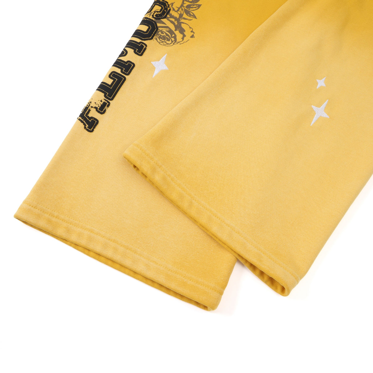 League Flare Sweatpants – Yellow – Close-up of stitched flared hems with white stars and partial black lettering