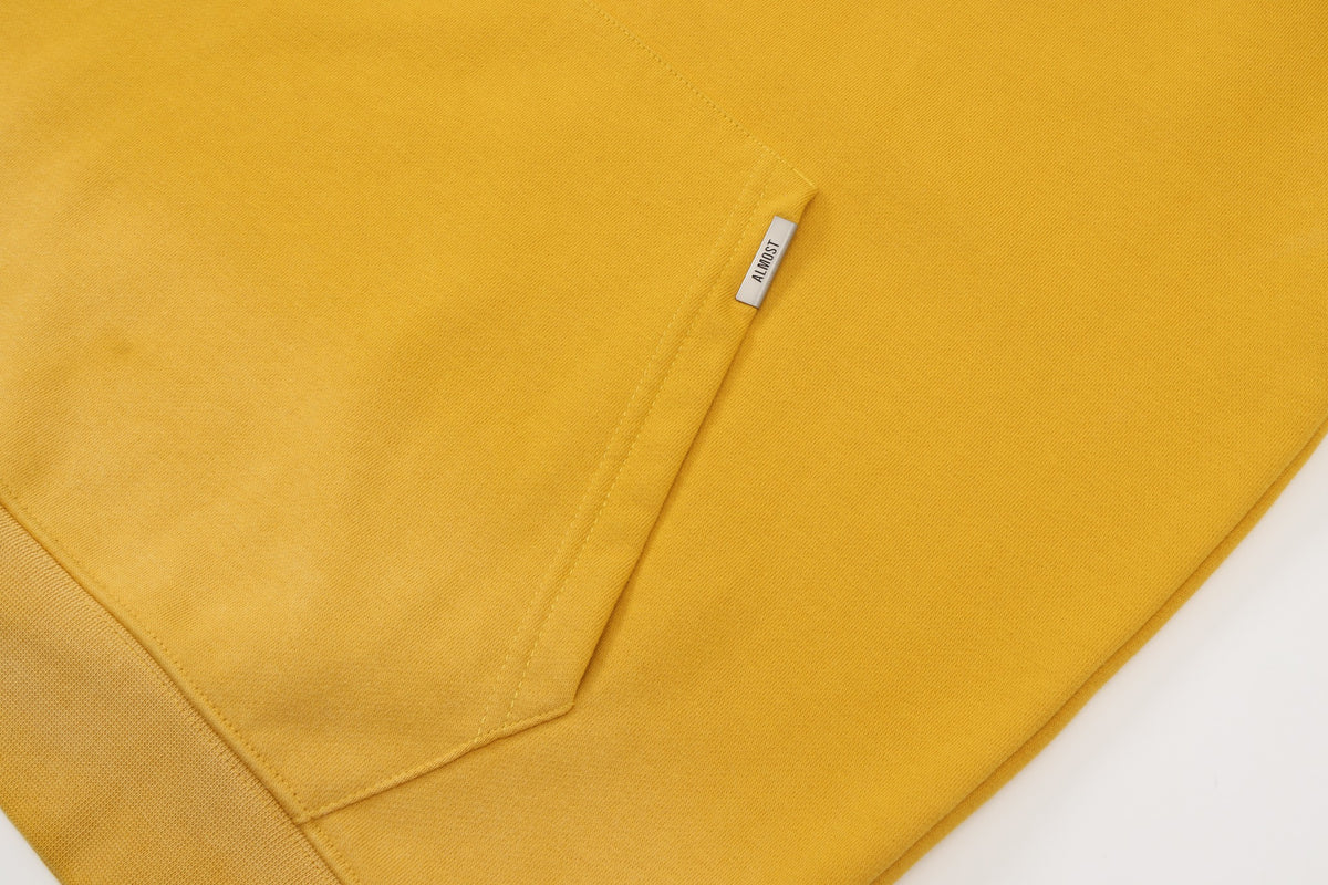 League Hoodie – Yellow – Close-up of kangaroo pocket with metal ALMOST logo tab