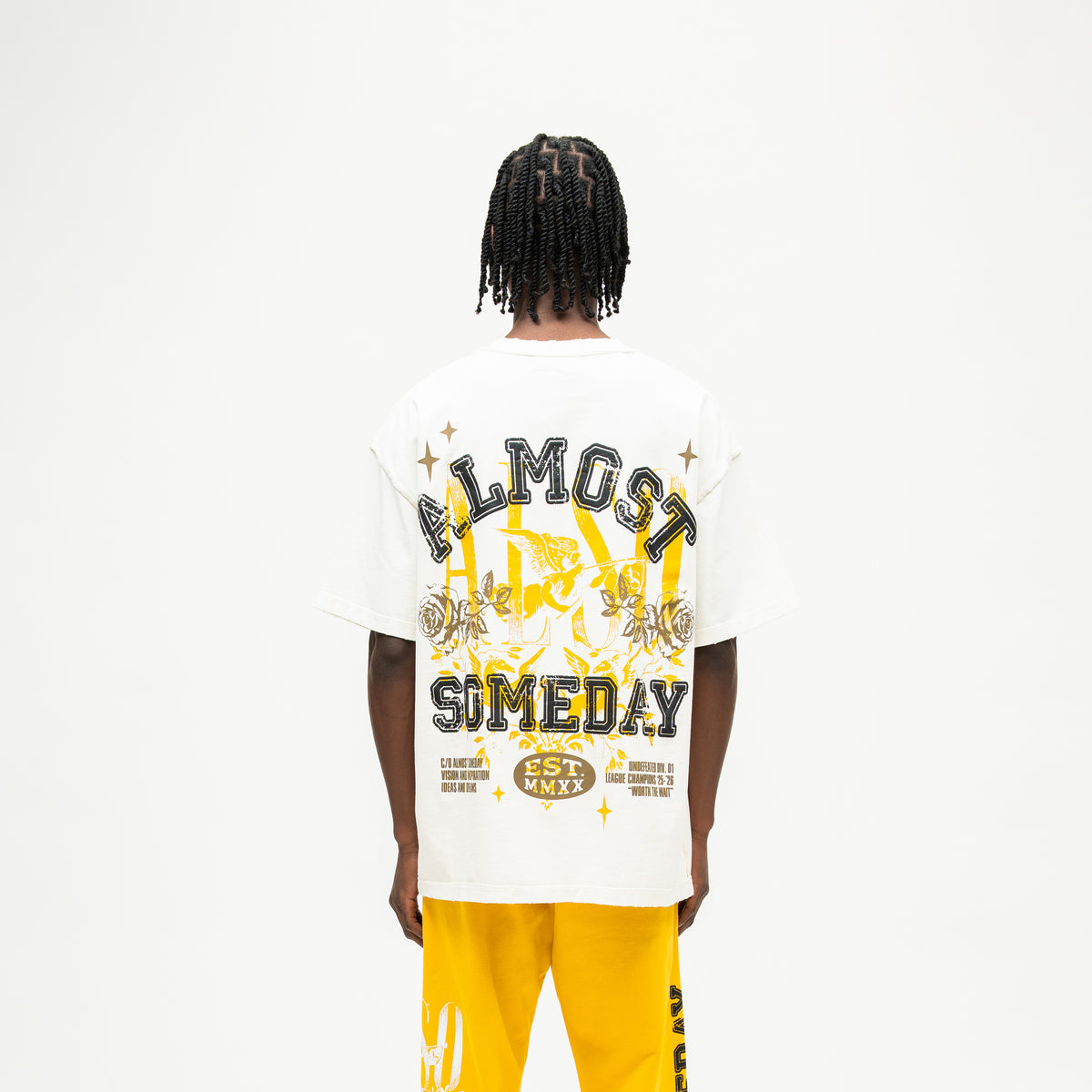 League Tee – Cream – Back view on model showing large ALMOST SOMEDAY lettering, cherub, roses, and stars