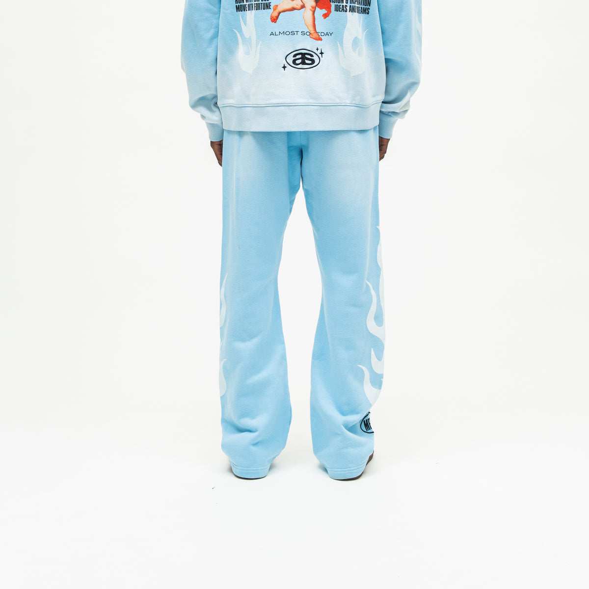 Members Flare Sweatpants – Light Blue – Back view on model showing plain seat, white flames along outer legs, and flared hems