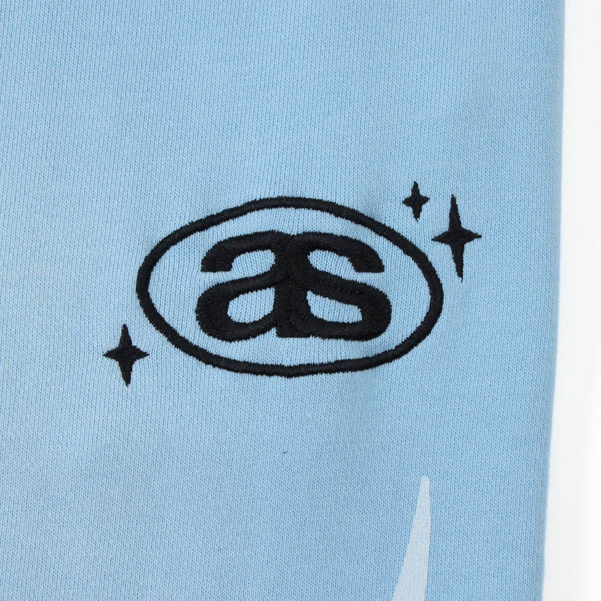 Members Flare Sweatpants – Light Blue – Close-up of black embroidered AS thigh logo and stars