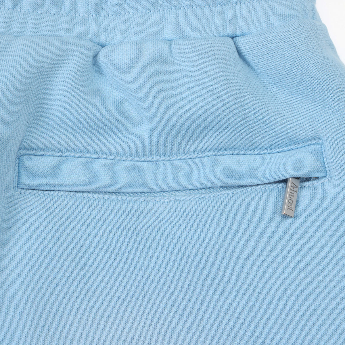 Members Flare Sweatpants – Light Blue – Close-up of zippered back pocket and branded metal zipper pull
