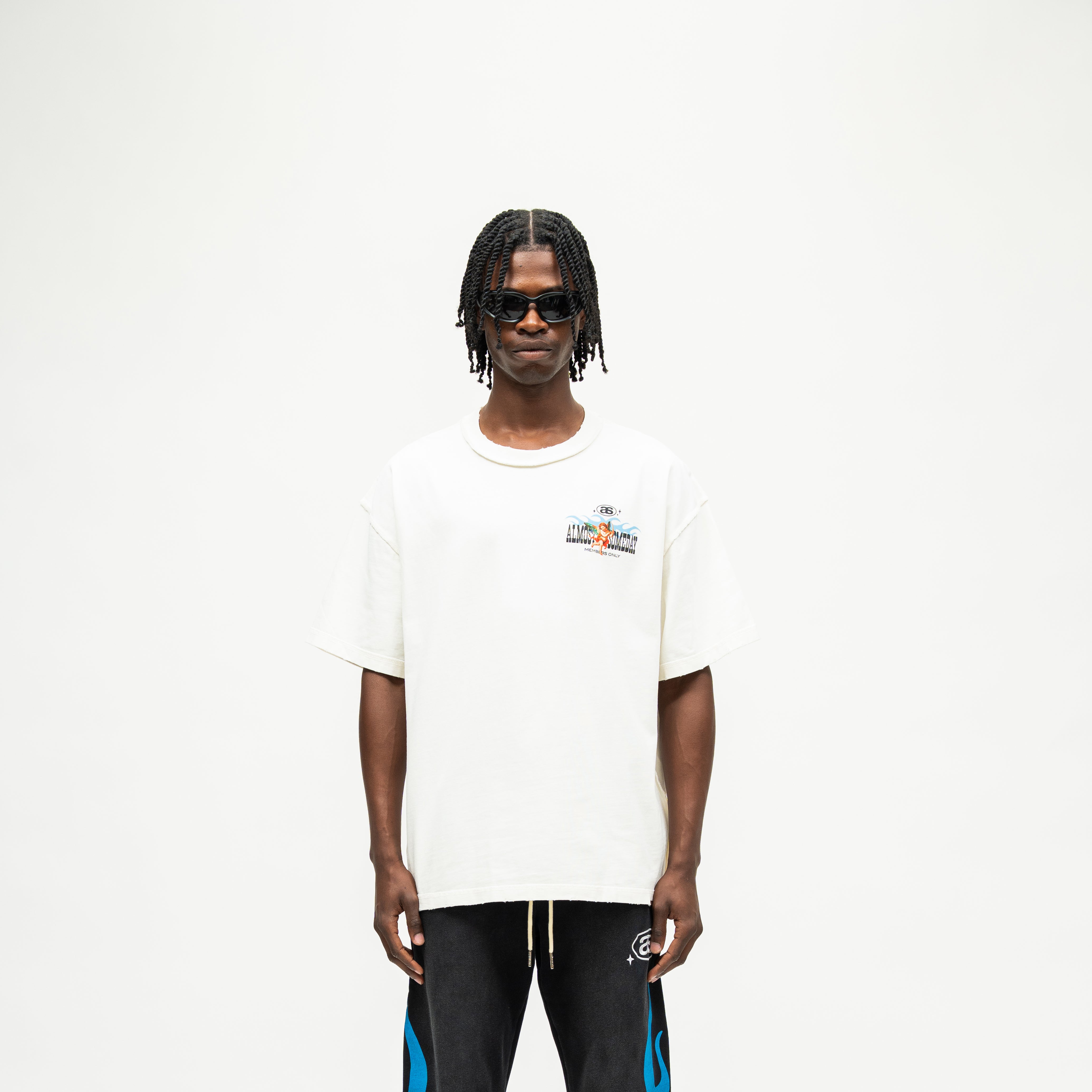 Members Tee – Cream – Front view on model showing small chest graphic, crew neckline, and wide short sleeves
