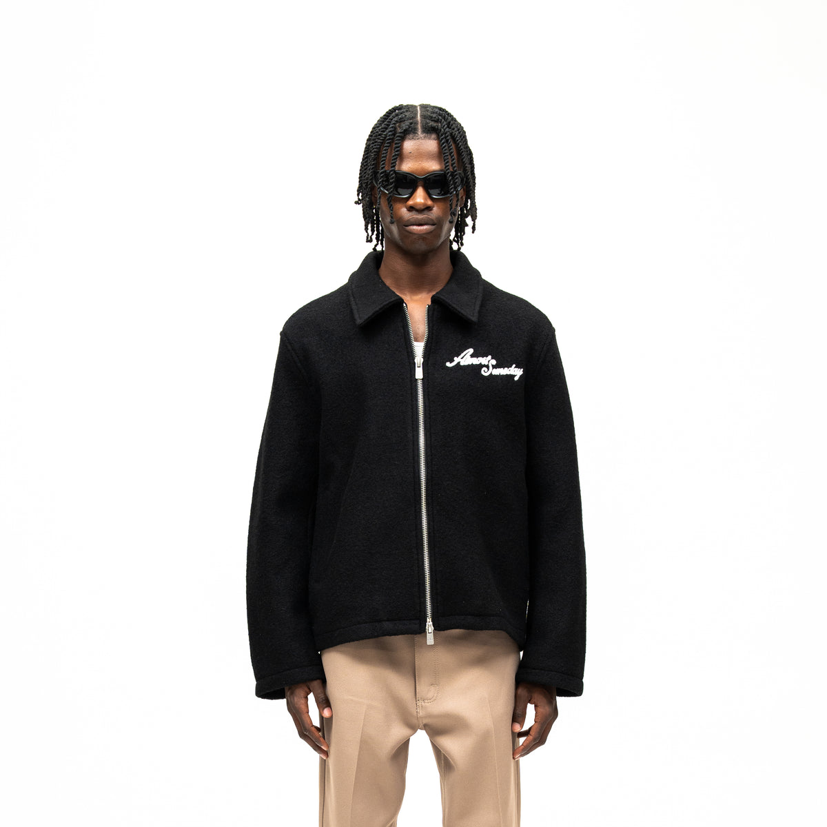 Saint Cropped Wool Jacket – Black – Front view on model showing pointed collar, silver-tone zip closure, and white script chest logo