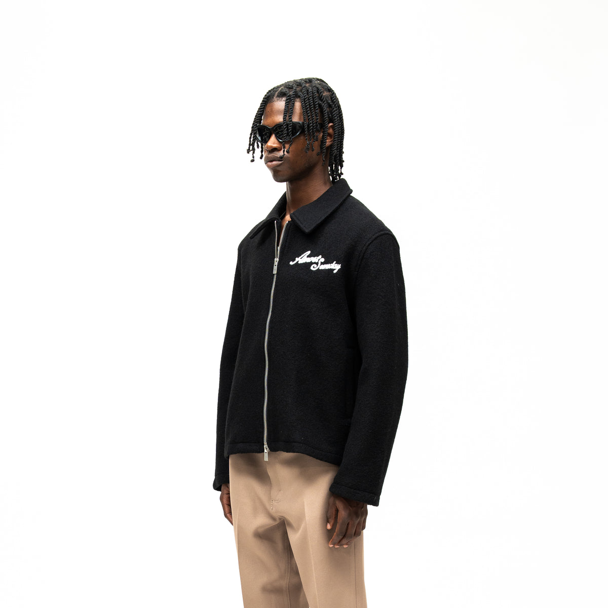 Saint Cropped Wool Jacket – Black – Three-quarter front view on model showing white chest lettering, pointed collar, and cropped hem