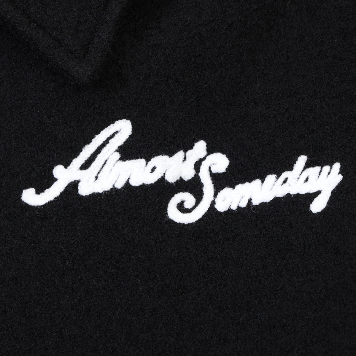 Saint Cropped Wool Jacket – Black – Close-up of white Almost Someday script chest logo