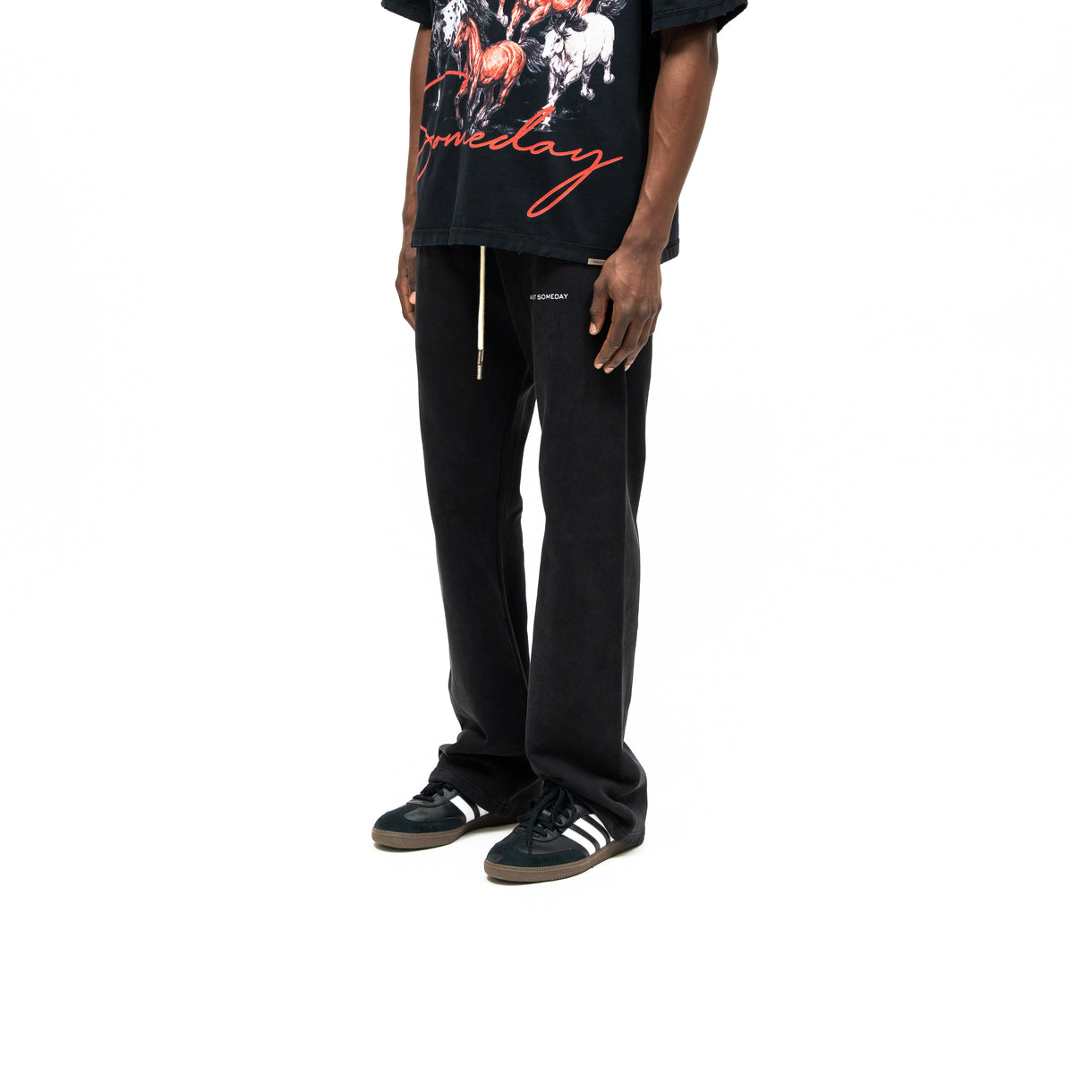 Smoke Flare Bottoms – Black – Three-quarter front view on model styled with graphic tee, showing thigh lettering and relaxed flared legs